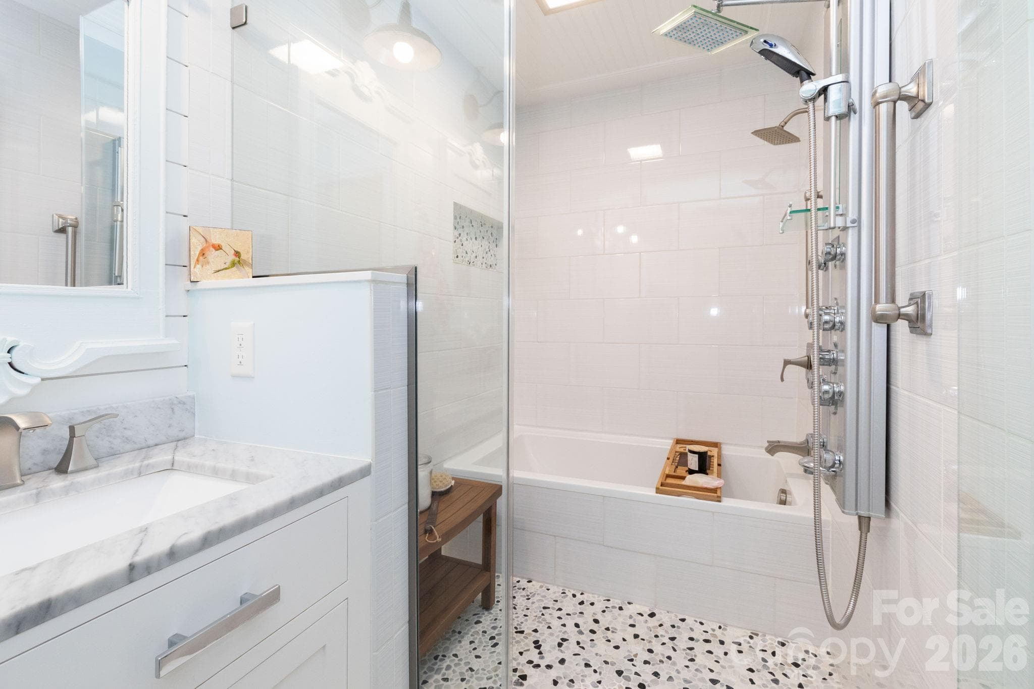 Glass-enclosed walk-in shower, separate tub, featuring white wall tile, a decorative accent band, pebble-style flooring, and multiple shower fixtures. - 139 Lone Eagle Lane, Hendersonville