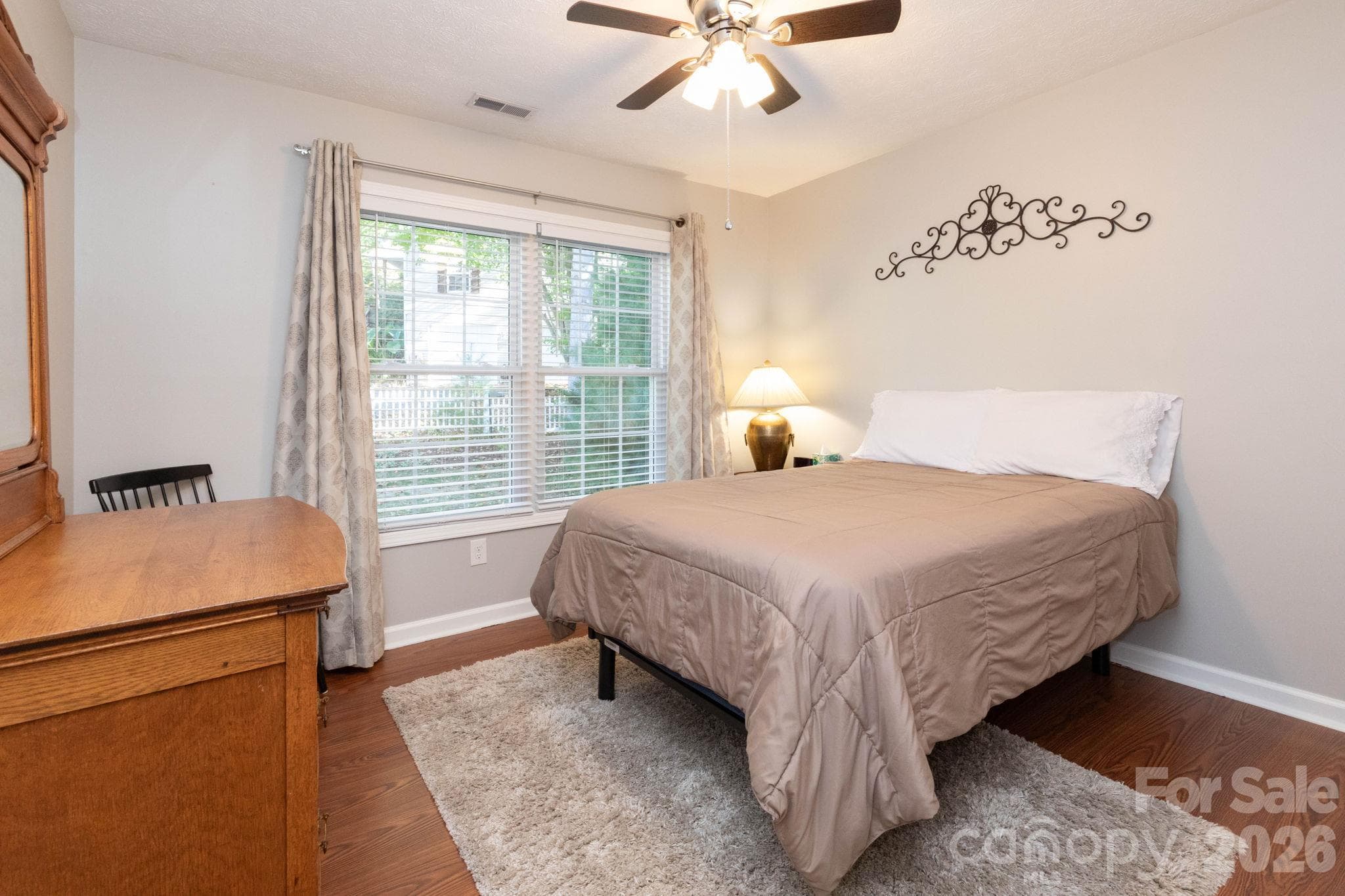 Inviting bedroom featuring warm wood flooring, a ceiling fan, and a large window overlooking the greenery outside. - 139 Lone Eagle Lane, Hendersonville