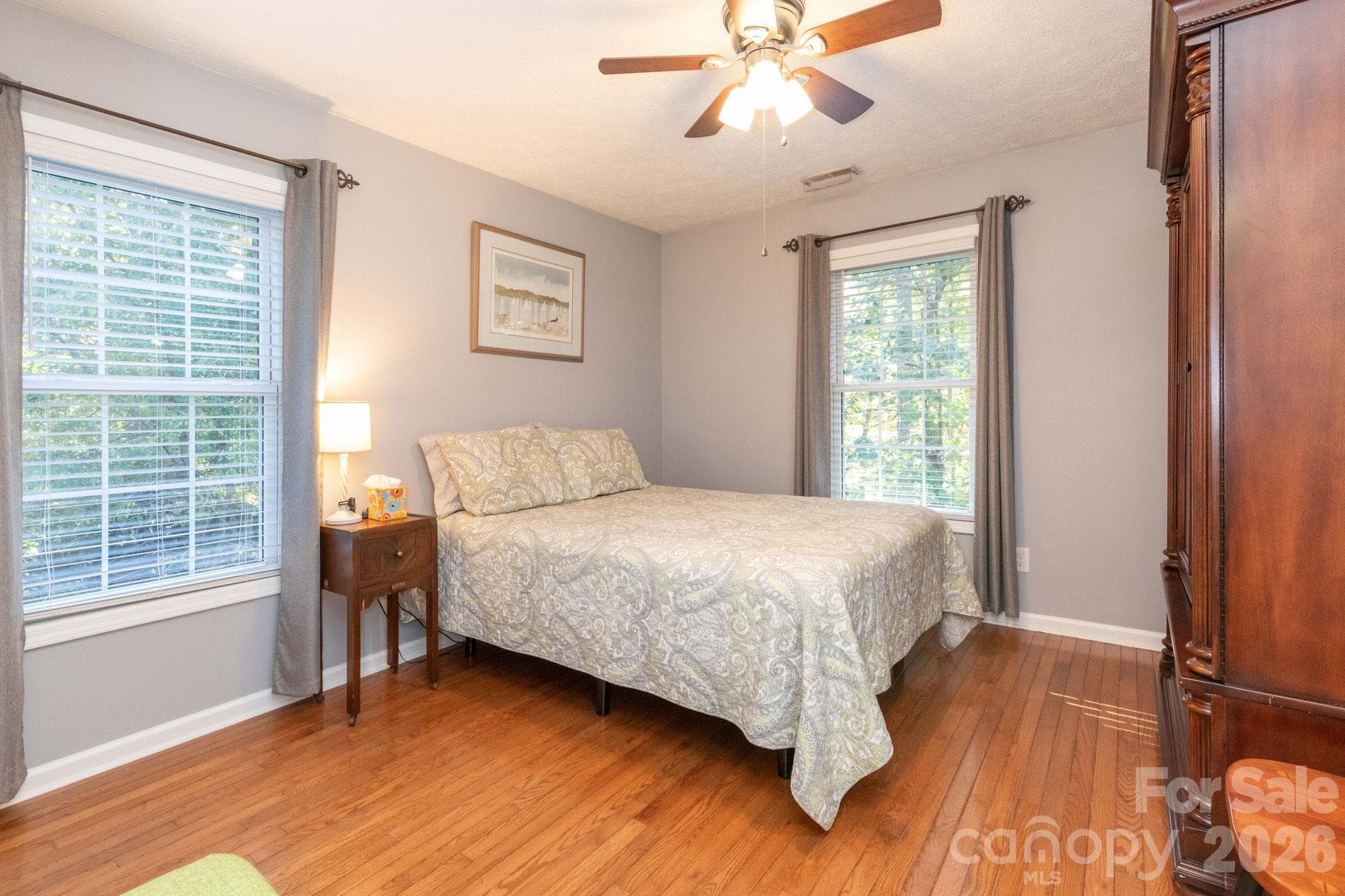 Bright bedroom with windows on two walls, wood flooring, and a ceiling fan for added comfort. - 139 Lone Eagle Lane, Hendersonville
