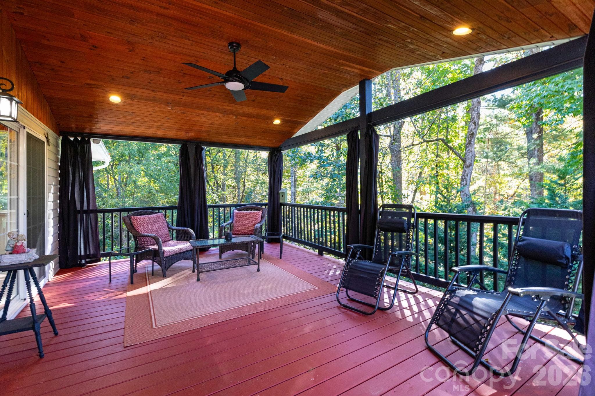Covered porch featuring a wood ceiling, recessed lighting, a ceiling fan, and peaceful views of the surrounding trees. - 139 Lone Eagle Lane, Hendersonville