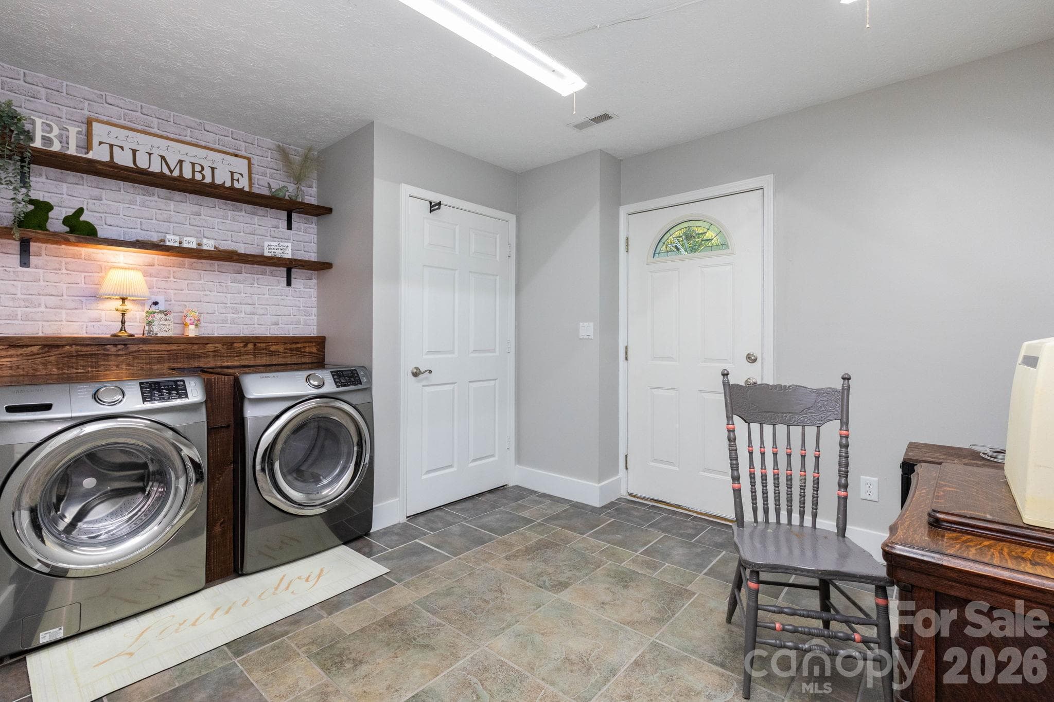 Laundry room with side-by-side washer and dryer space, open shelving, a folding counter, and an exterior entry door. - 139 Lone Eagle Lane, Hendersonville