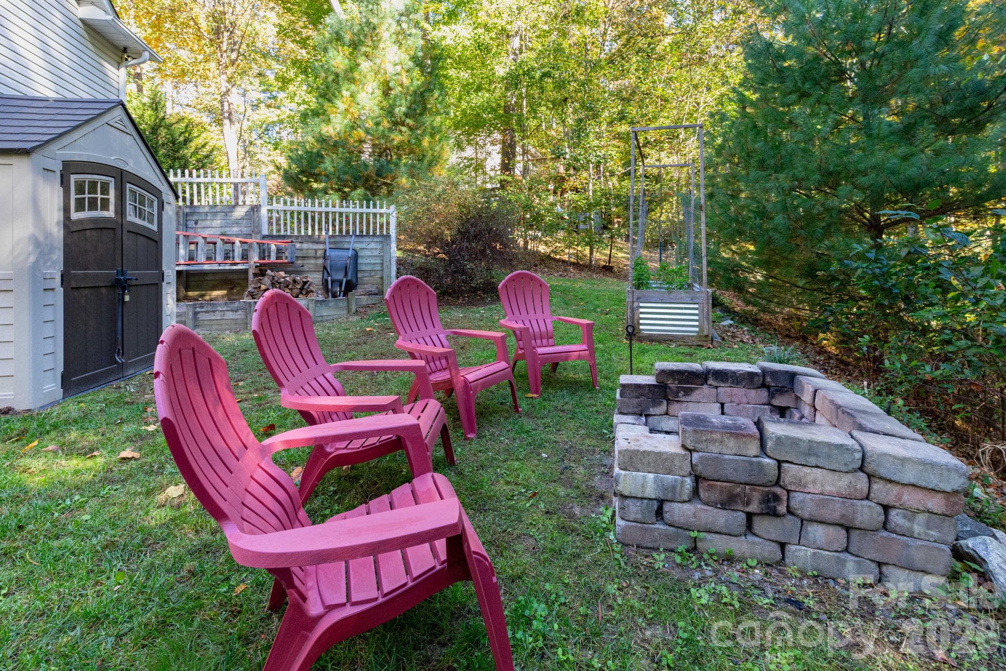 Backyard gathering area featuring a stone fire pit, space for outdoor seating, and a wooded backdrop. - 139 Lone Eagle Lane, Hendersonville