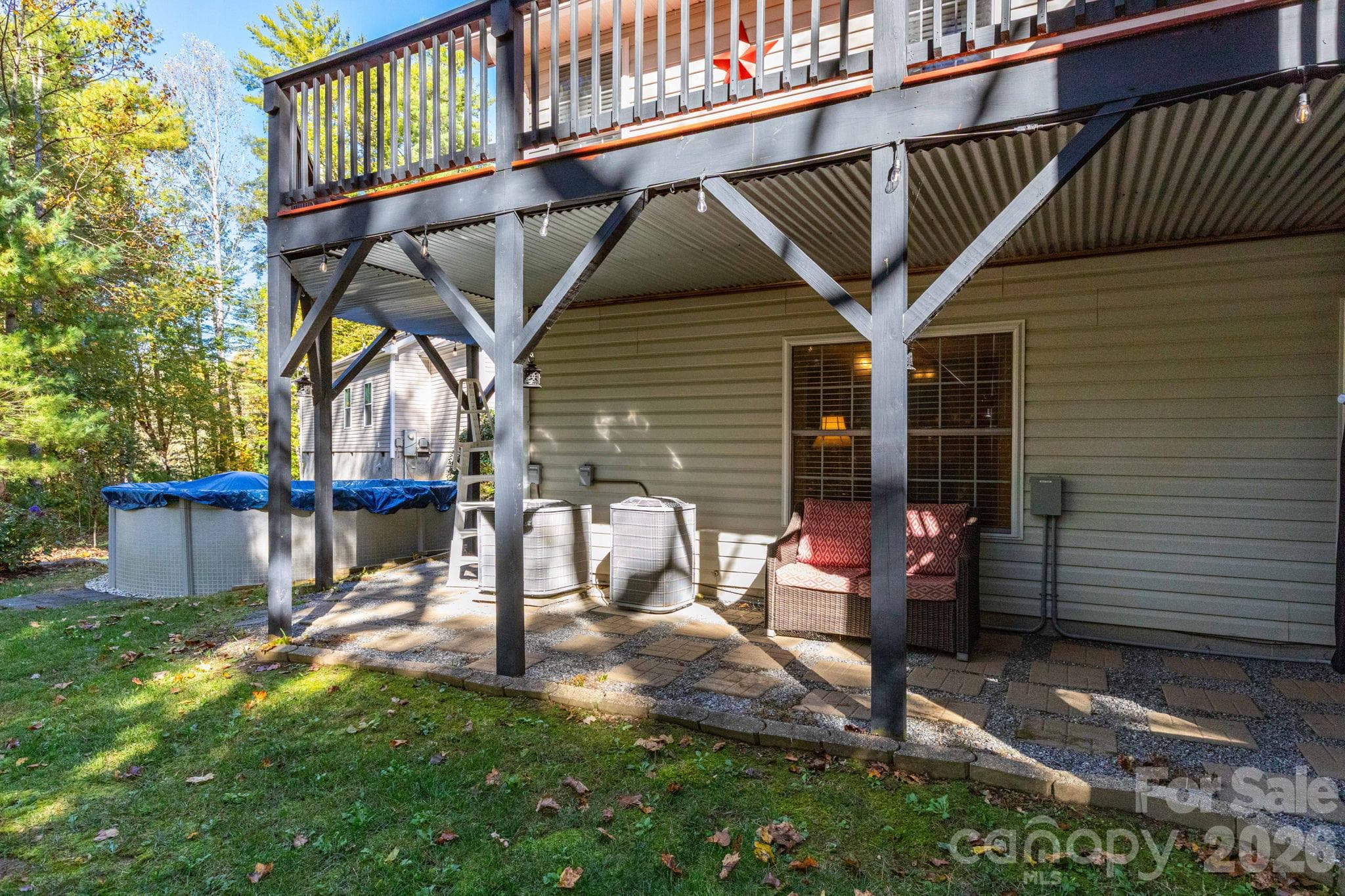 Lower-level patio beneath the elevated deck offers shaded outdoor seating and direct access to the backyard and above ground pool. - 139 Lone Eagle Lane, Hendersonville