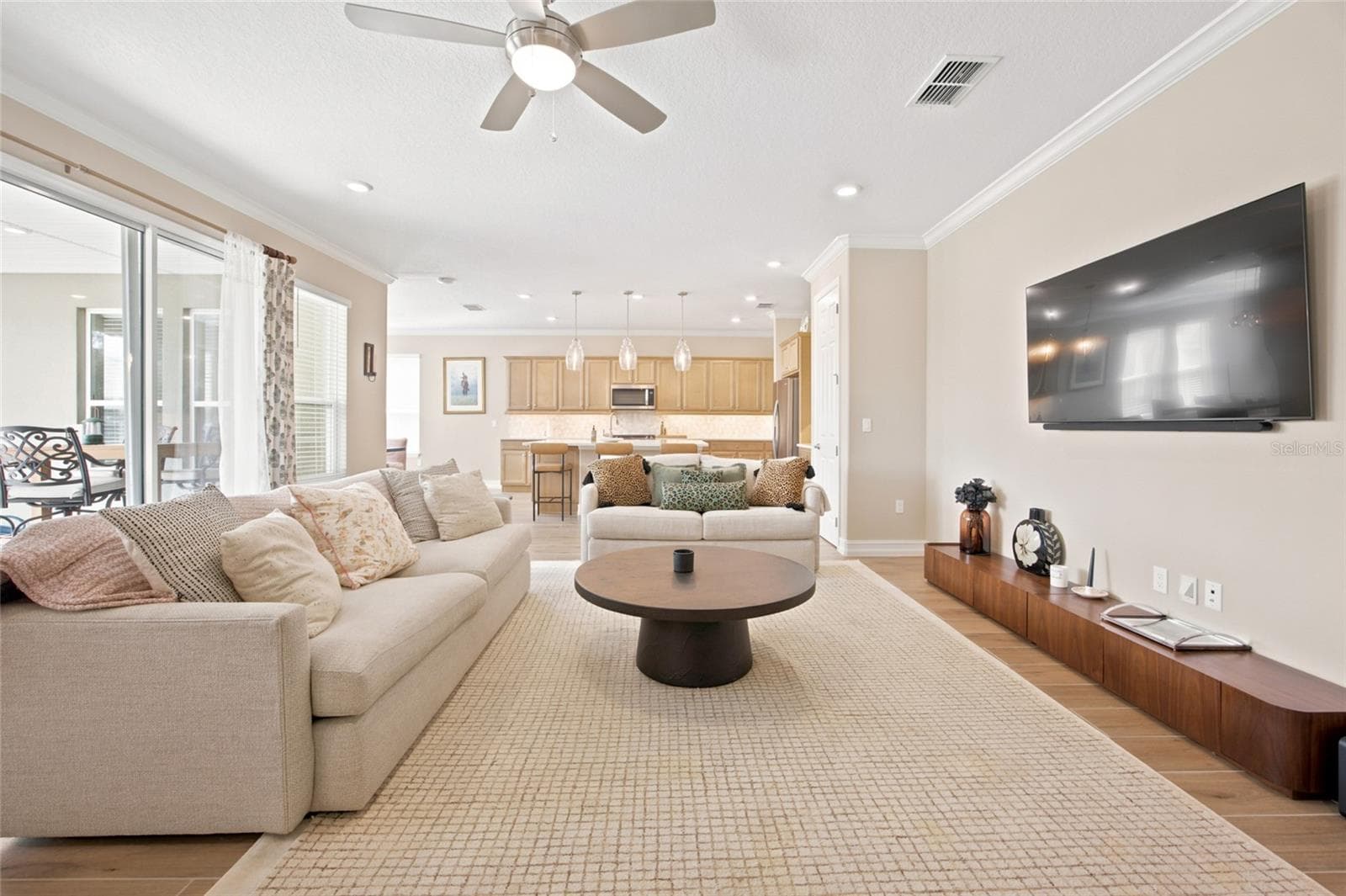 Spacious living room offering an open view into the kitchen and access to the covered patio. - 4497 NW 54TH TER, OCALA