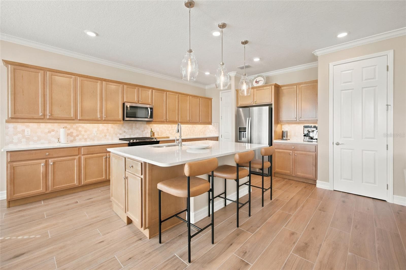 Beautifully appointed kitchen with expansive cabinetry, a central island and breakfast-bar seating. - 4497 NW 54TH TER, OCALA