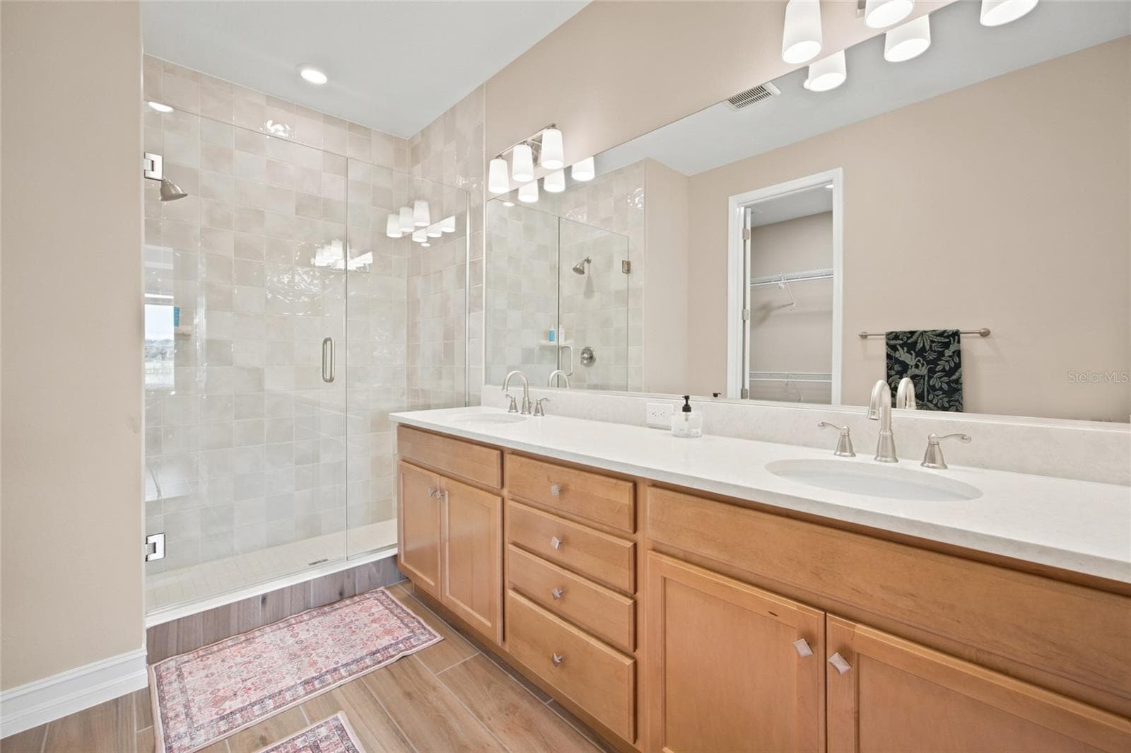 Primary bathroom featuring dual sinks, generous vanity space and a glass-enclosed shower. - 4497 NW 54TH TER, OCALA