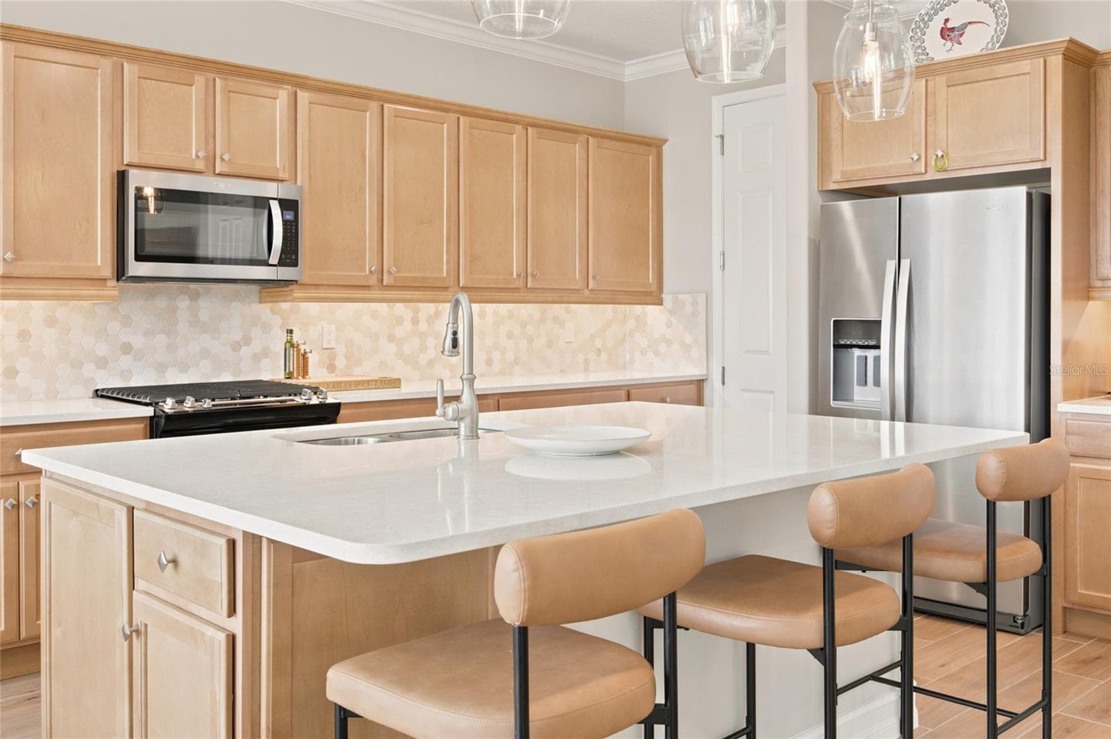 Kitchen island with seating for three, pendant lighting and stainless steel appliances. - 4497 NW 54TH TER, OCALA