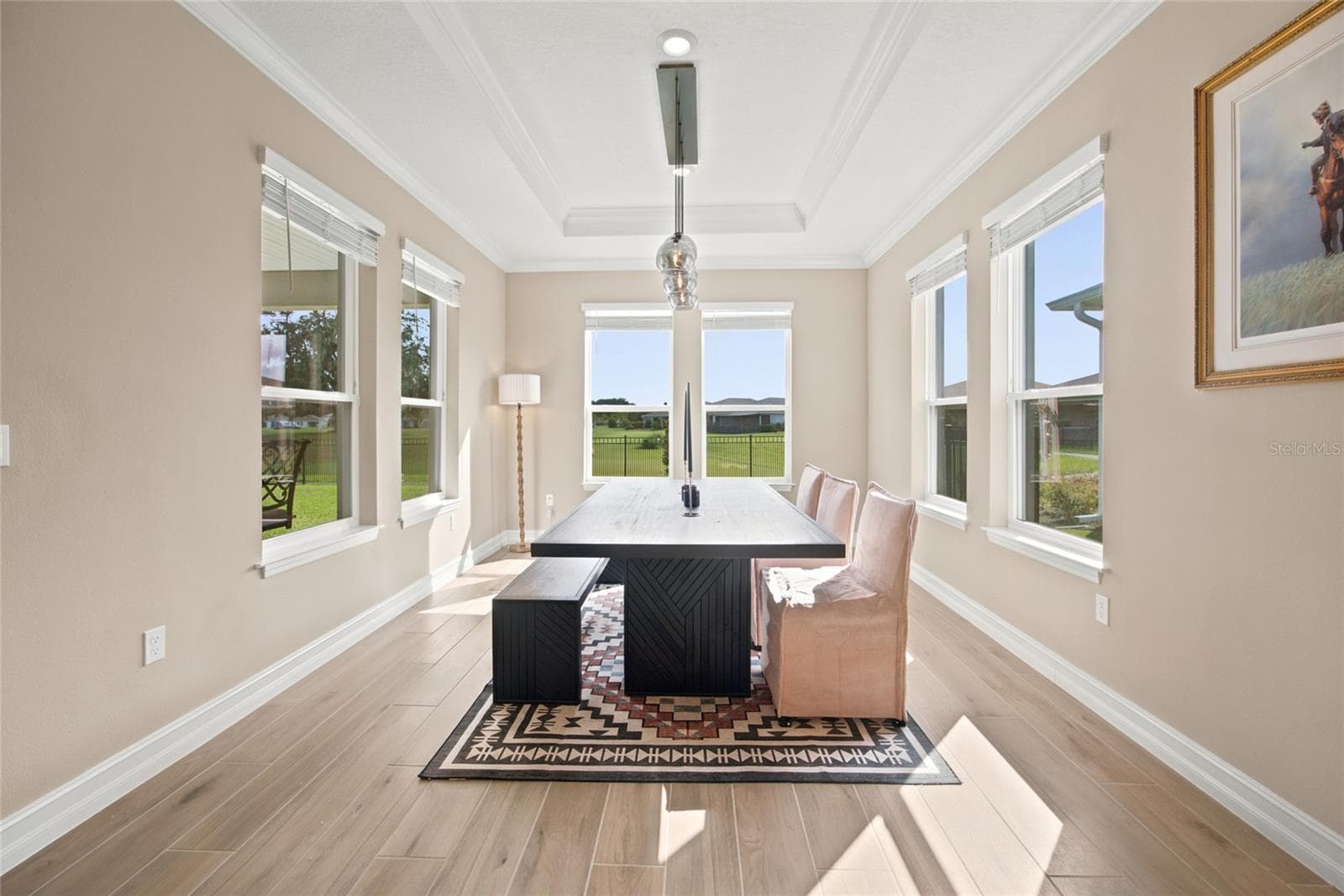 Bright dining room surrounded by windows with views toward the rear green space. - 4497 NW 54TH TER, OCALA
