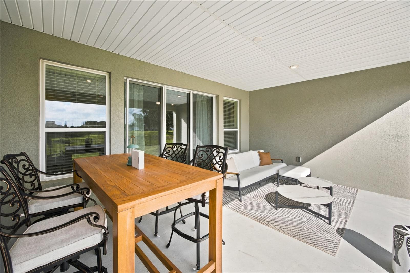 Covered patio offering separate seating and dining areas for outdoor enjoyment. - 4497 NW 54TH TER, OCALA