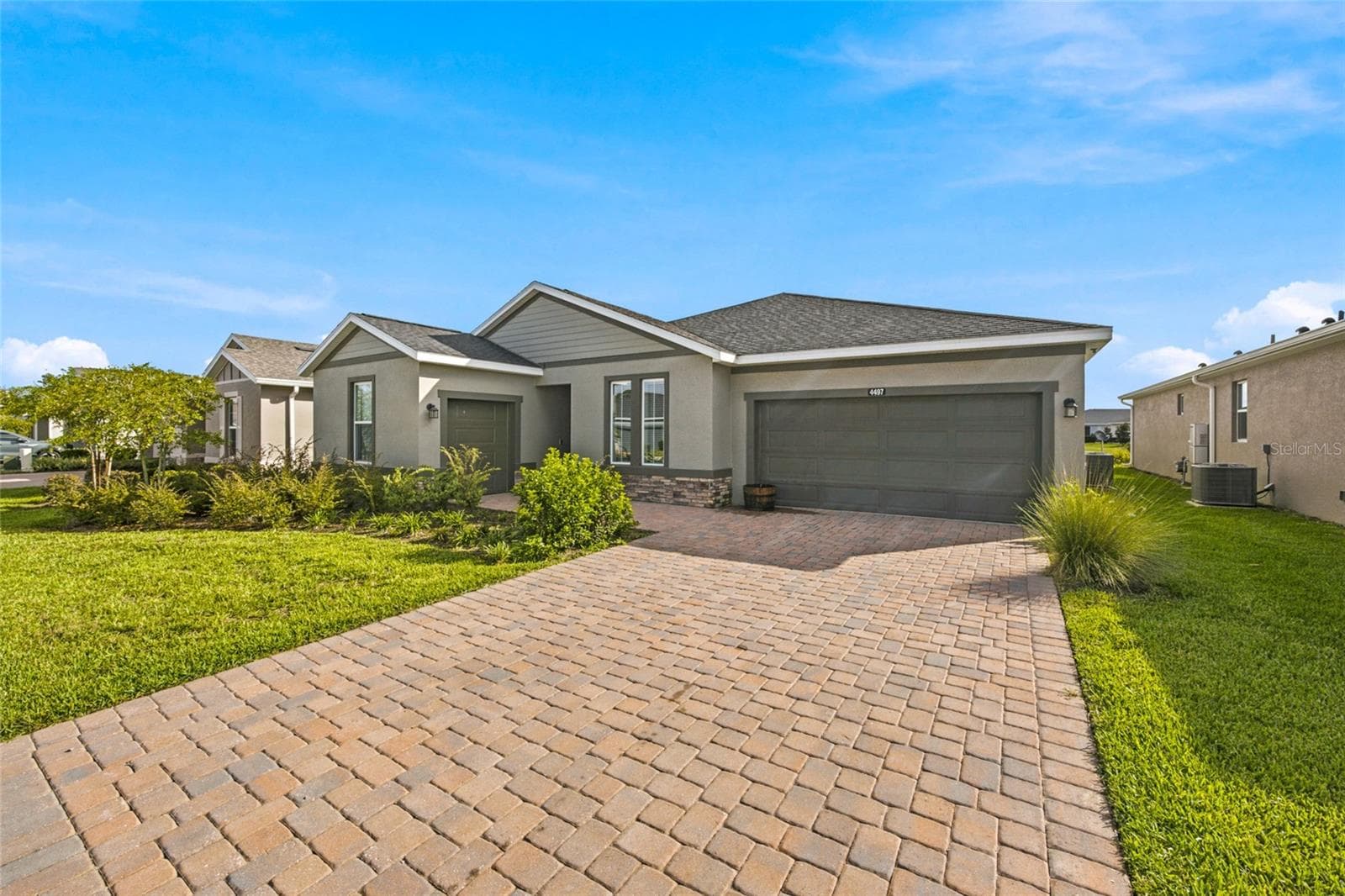 Angled exterior view highlighting the attractive paver driveway and landscaping. - 4497 NW 54TH TER, OCALA