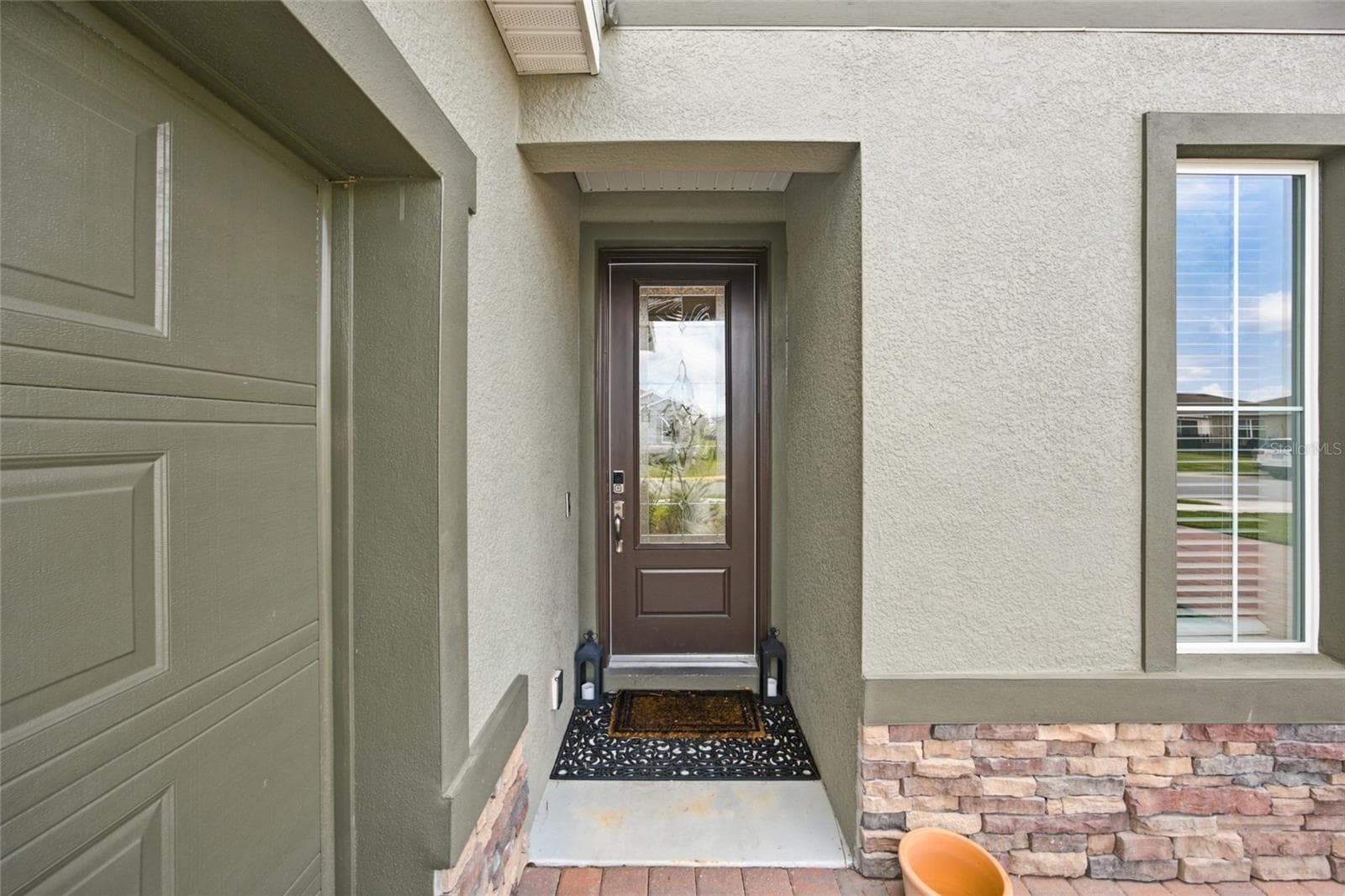 Recessed front entry with decorative glass front door and stone detailing. - 4497 NW 54TH TER, OCALA