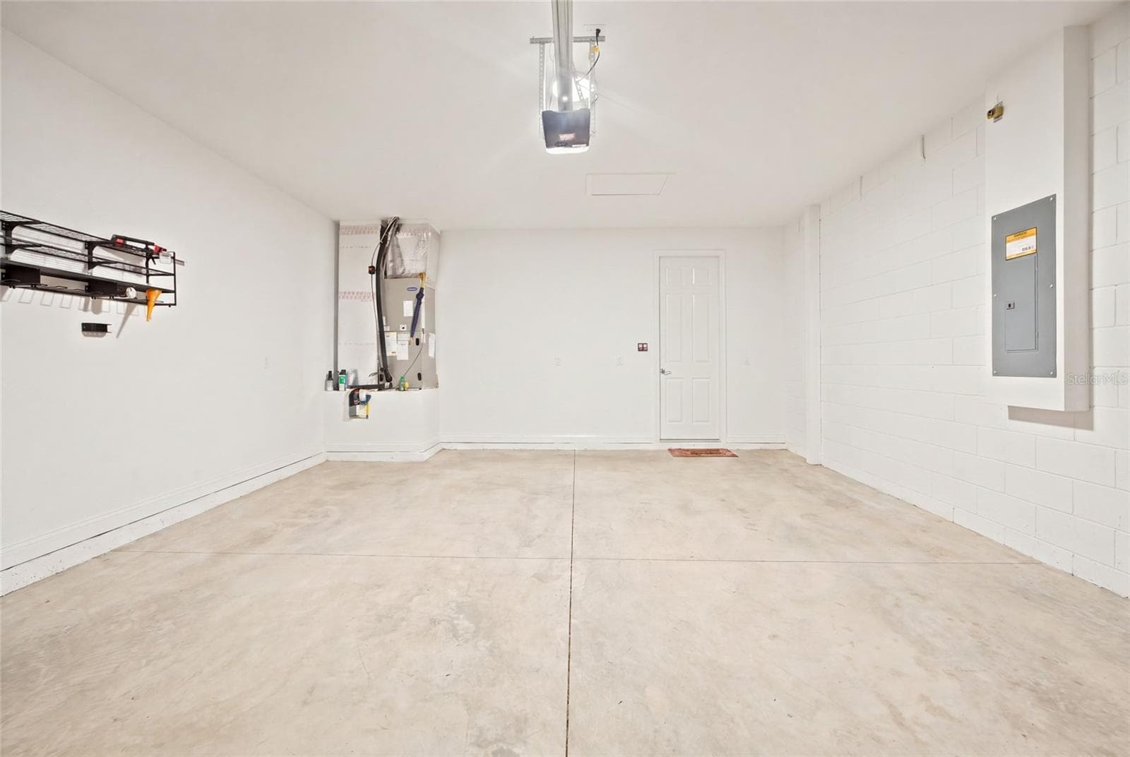 Two-car garage with concrete flooring and overhead storage rack. - 4497 NW 54TH TER, OCALA