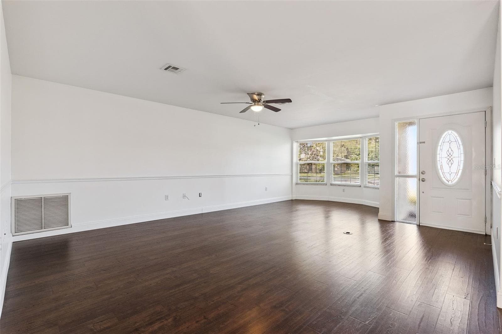 A bright living room with a bay window and rich wood-look floors - 5246 ROYAL OAK DR, FRUITLAND PARK