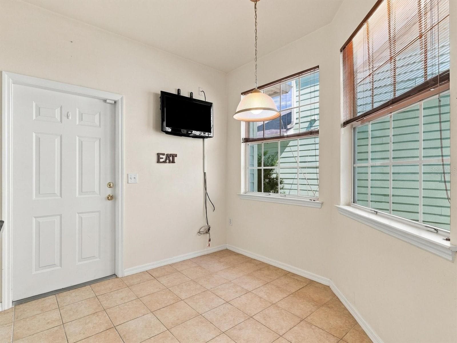 Virtually Staged - Dinette & Kitchen with light from windows, mounted tv, and door to garage. - 11644 NW 18TH PL, GAINESVILLE