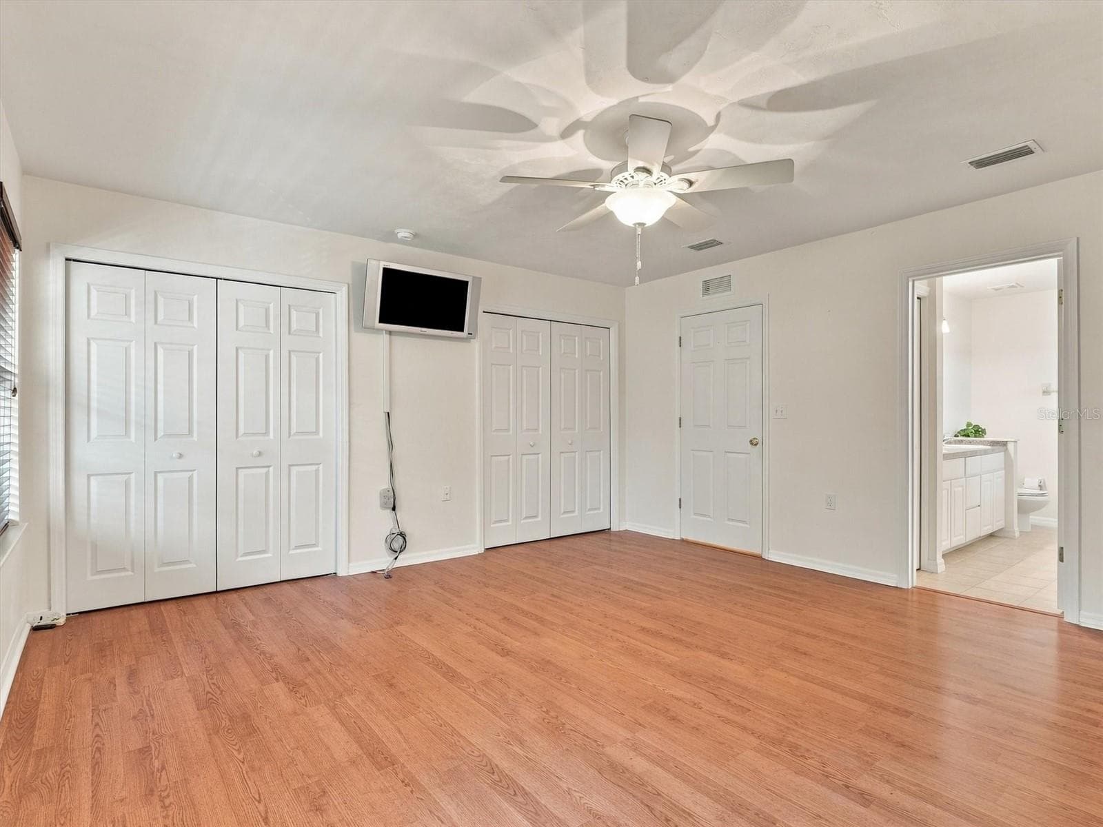 Primary Bedroom, Dual Closets, En-Suite Bathroom, Mounted TV, door to hallway. - 11644 NW 18TH PL, GAINESVILLE
