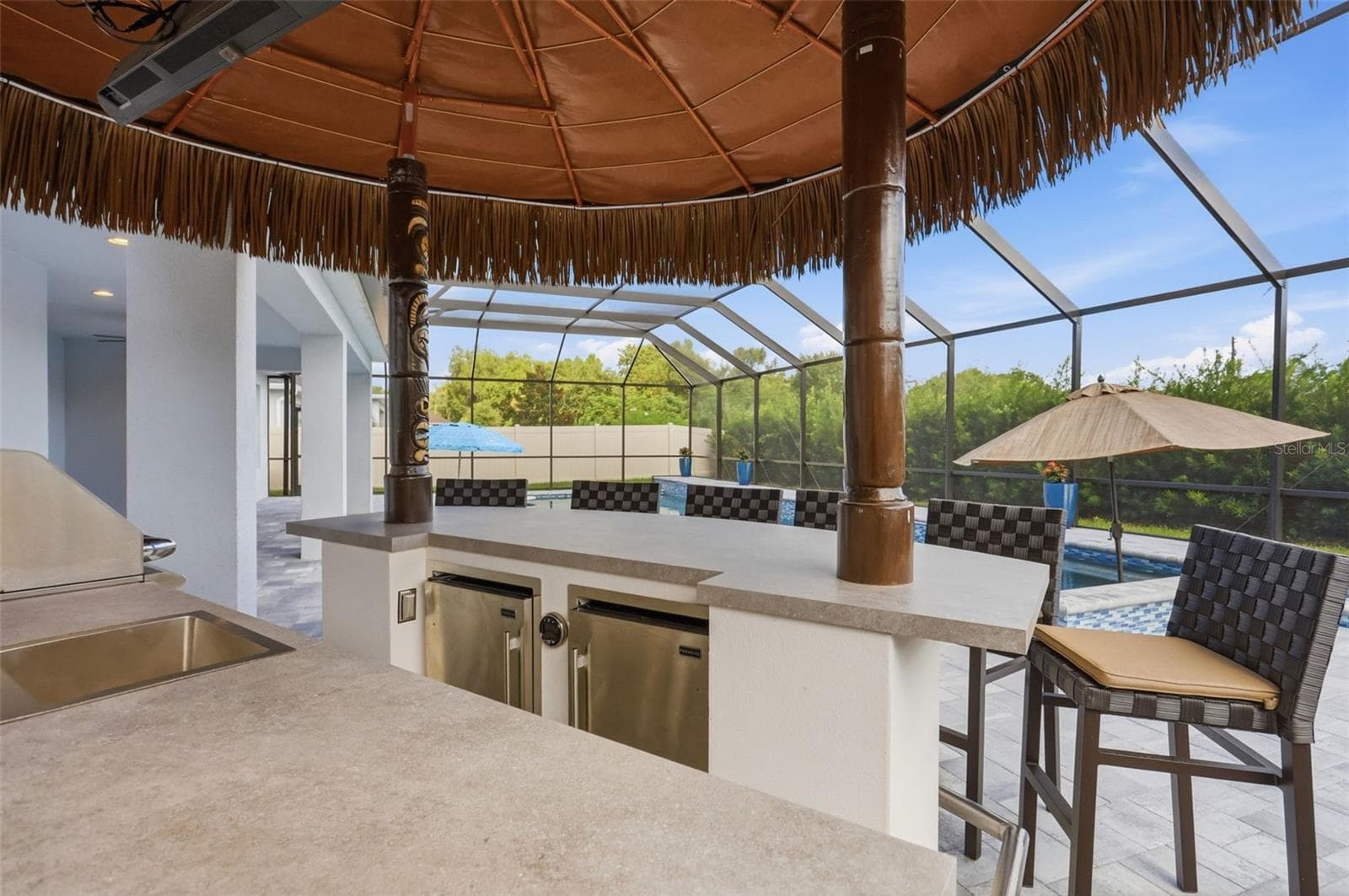 Summer kitchen includes a grill, two refrigerators, large entertaining bar, and remote pull down TV - 1552 MYRTLE OAKS TRL, OVIEDO