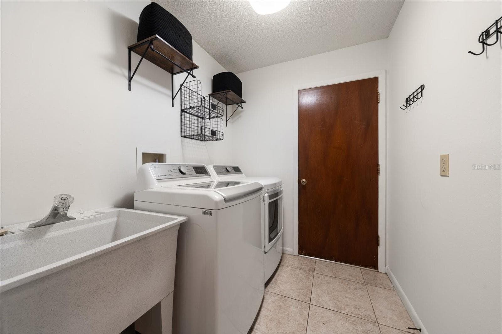 Update laundry room with sink and shelving and access to the large garaage with tiled flooring and a workshop area. - 1105 DEER RUN PL, VALRICO