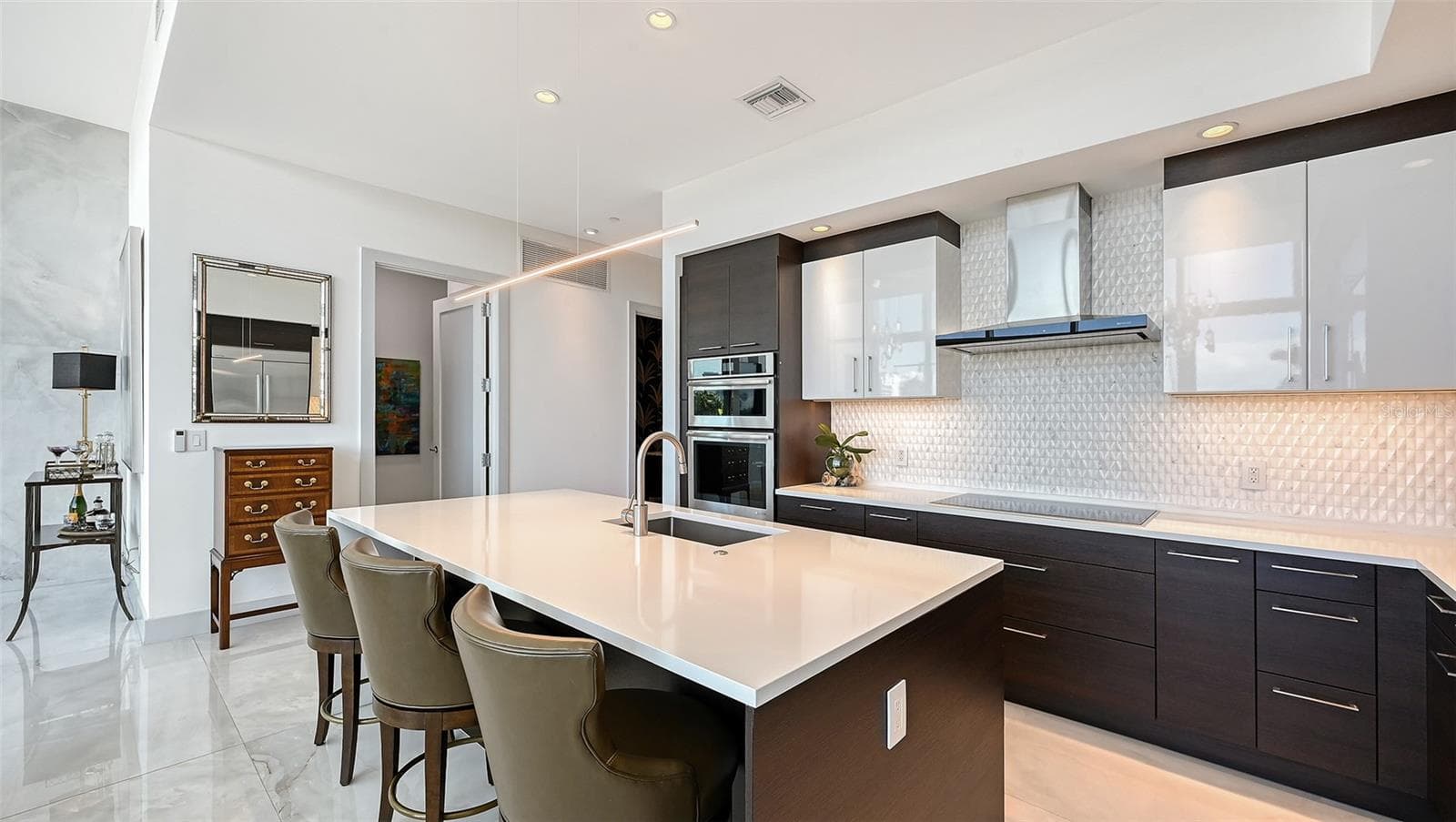 Open-concept kitchen featuring rich dark cabinetry, sleek countertops, and a spacious island with bar seating - 1155 N GULFSTREAM AVE #207, SARASOTA