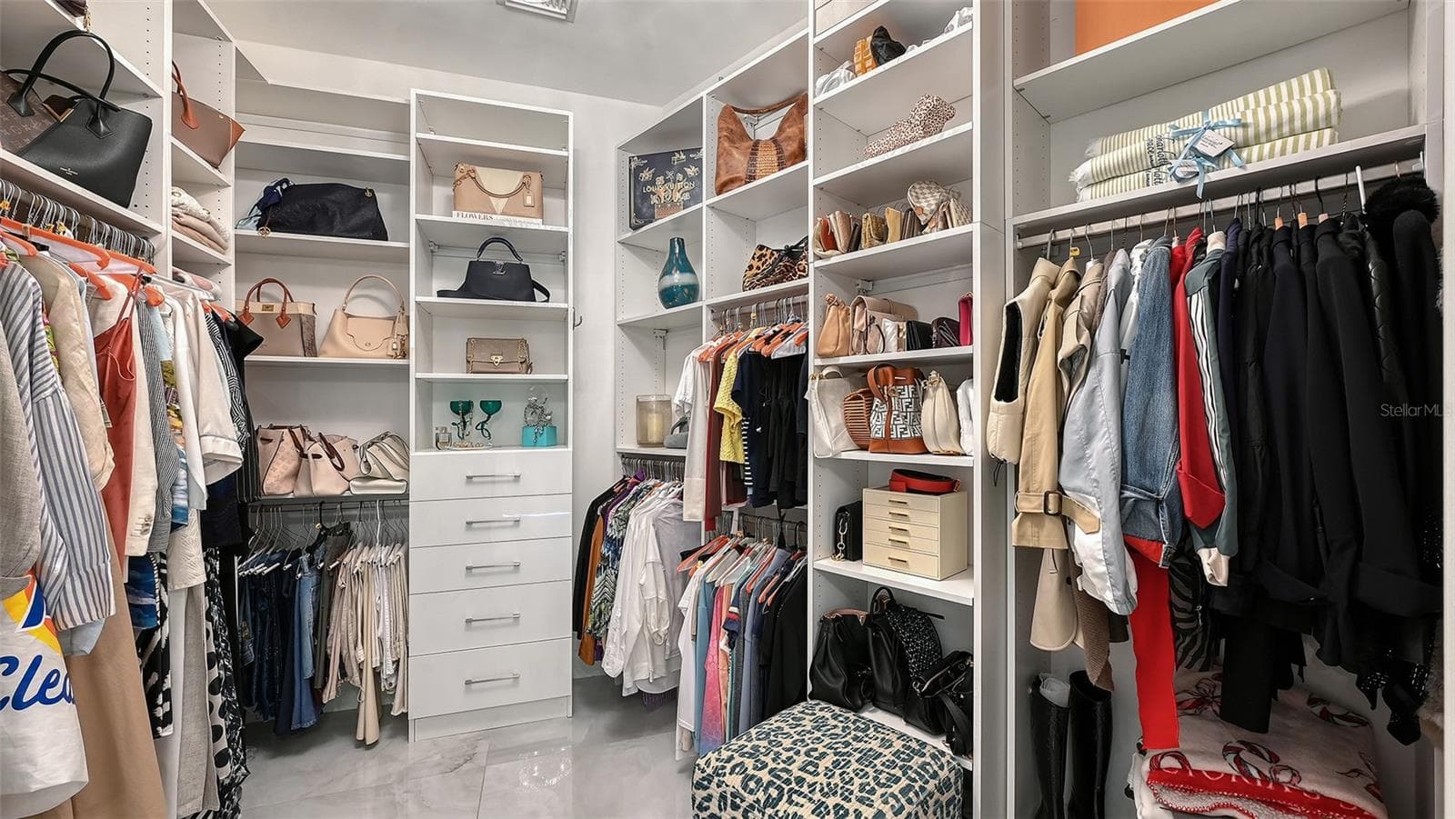 Custom-designed primary closet with elegant display areas and refined, organized storage. - 1155 N GULFSTREAM AVE #207, SARASOTA