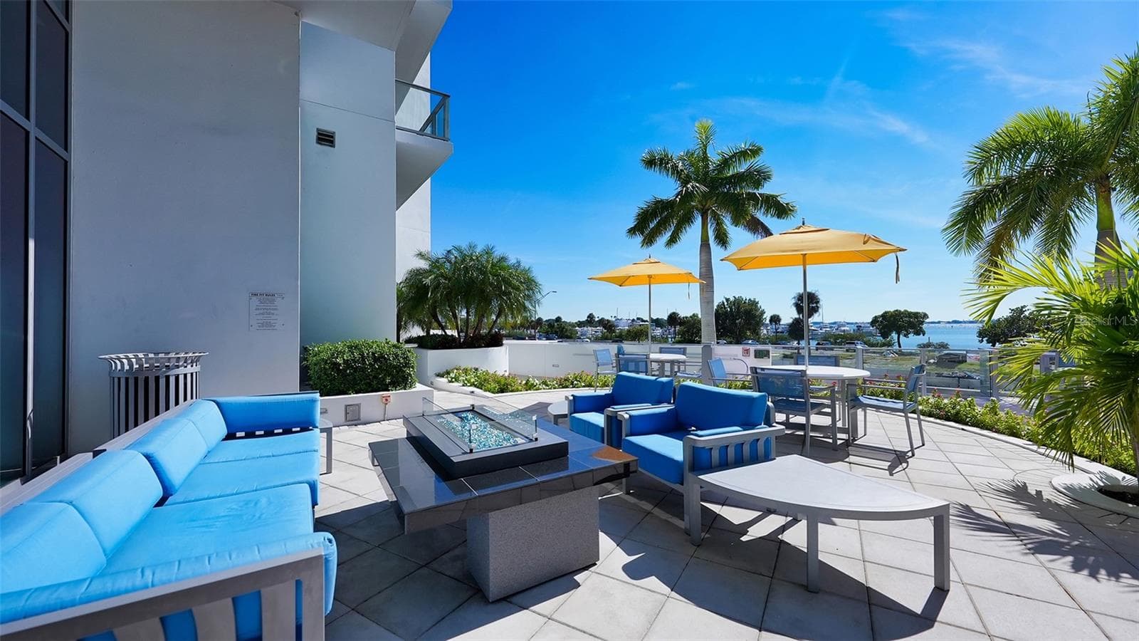 An inviting poolside seating area with a fire pit, perfect for relaxed gatherings, evening conversations, and entertaining under the stars. - 1155 N GULFSTREAM AVE #207, SARASOTA