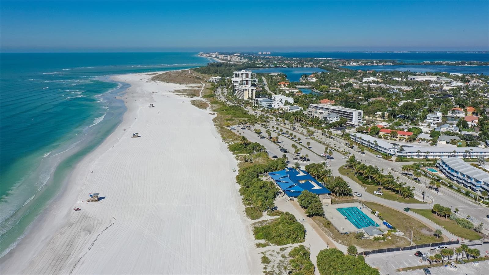 A breathtaking aerial view of Lido Beach, showcasing pristine white sands and brilliant turquoise waters along Sarasota’s stunning Gulf Coast. - 1155 N GULFSTREAM AVE #207, SARASOTA