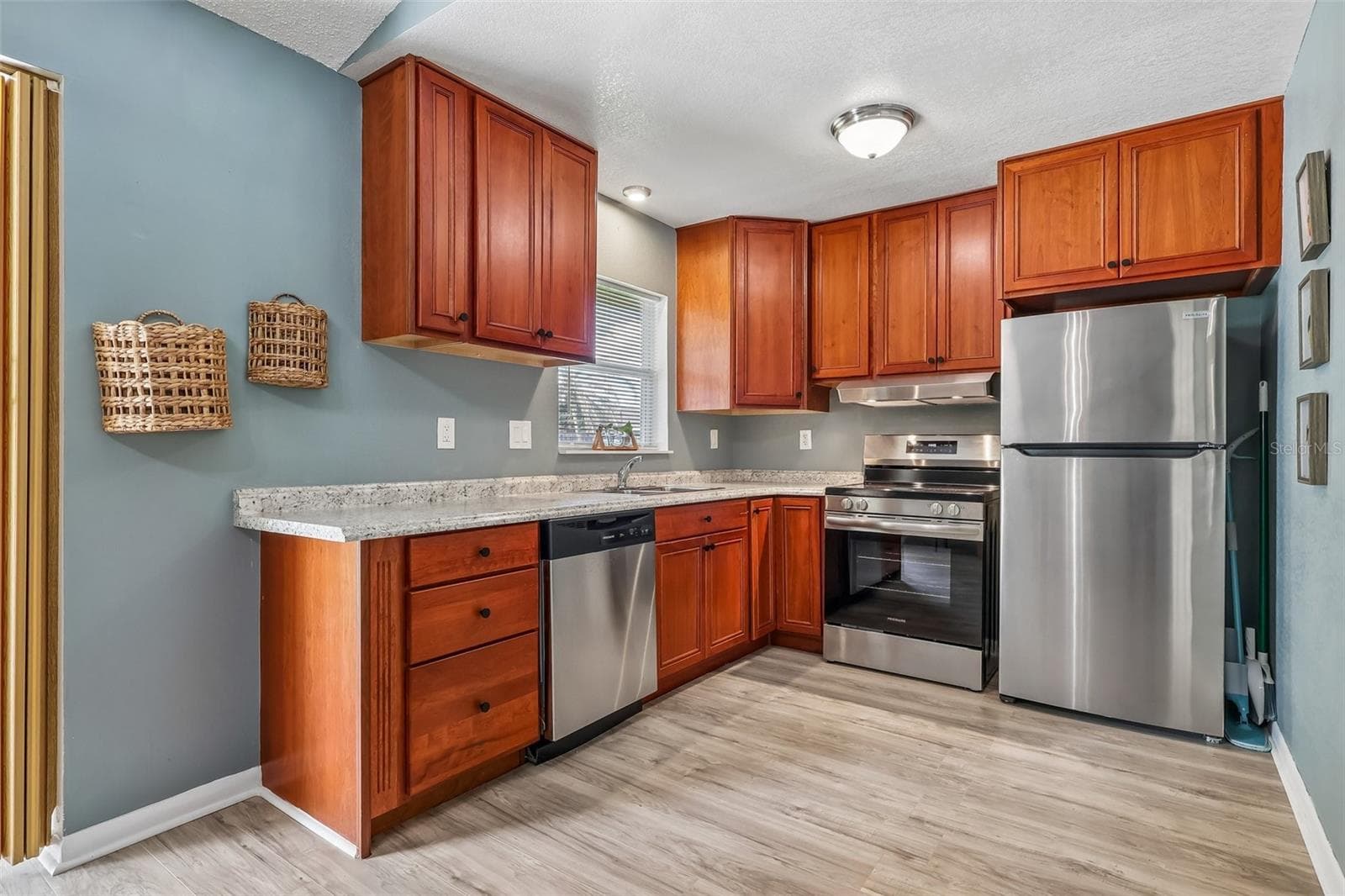 Beautiful updated kitchen! The reddish wood cabinets offer a warmth to the home and there are stainless steel appliances for a sleek look - 1332 BOREAS DR, ORLANDO
