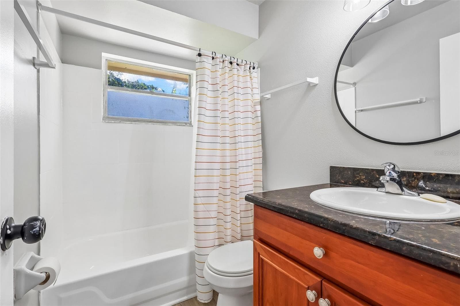 The guest bathroom features a tub/shower combo, updated vanity, and a decorative mirror - 1332 BOREAS DR, ORLANDO