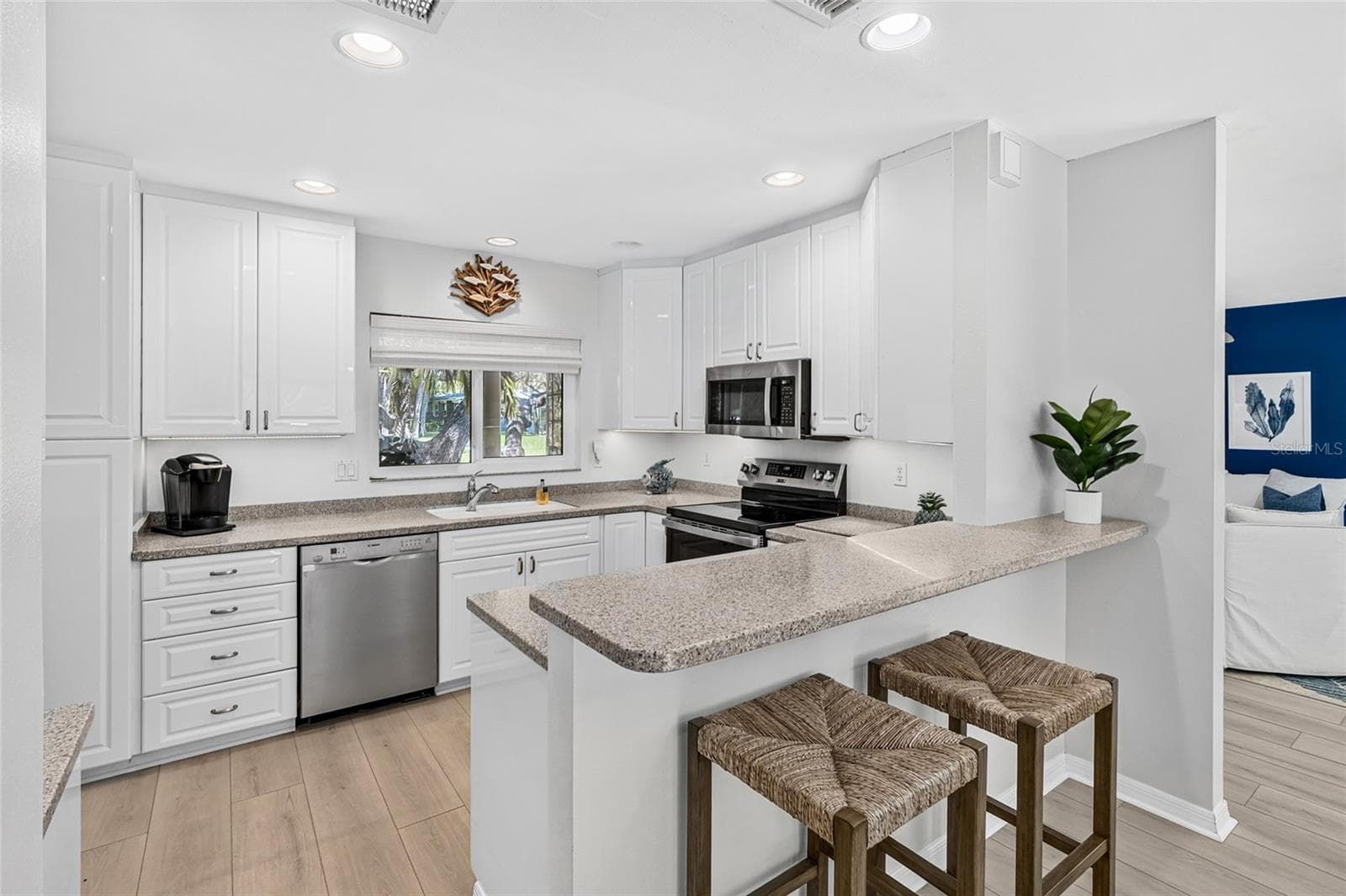 Bright white kitchen offers generous cabinetry, stone counters, stainless appliances and plenty of gathering space. - 5376 SHADOW LAWN DR, SARASOTA