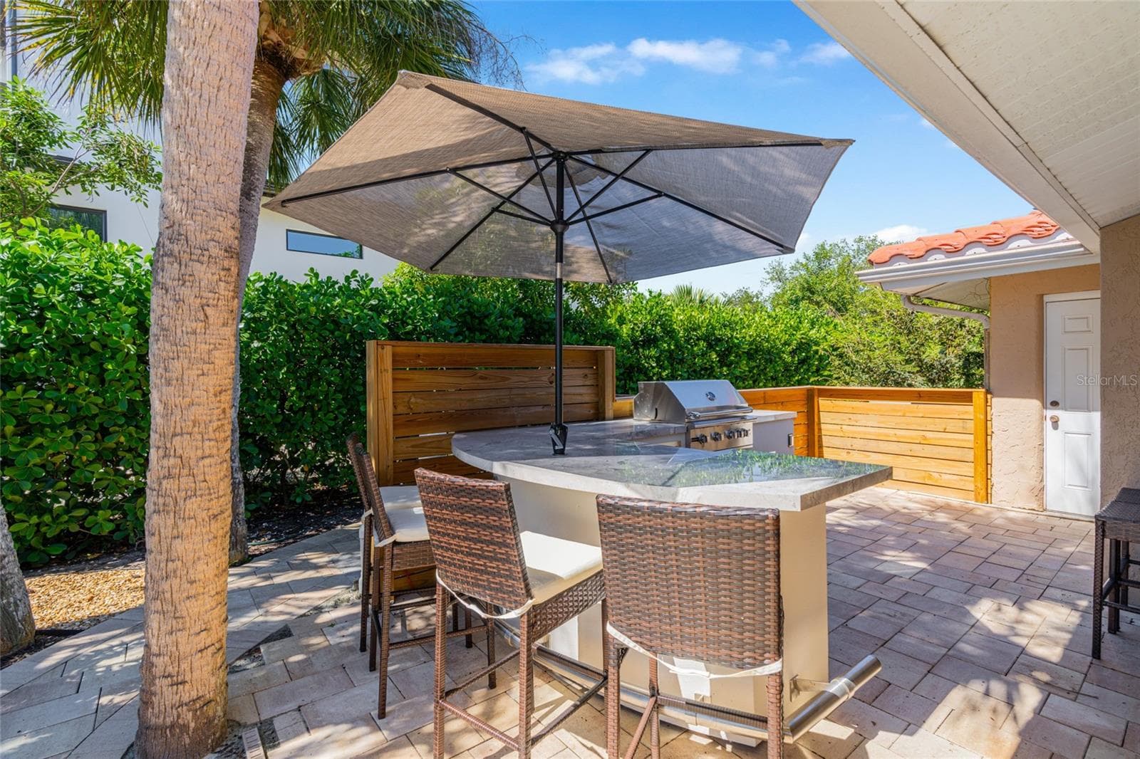 Outdoor kitchen and dining area make poolside entertaining easy and extend the home's living space outdoors. - 5376 SHADOW LAWN DR, SARASOTA