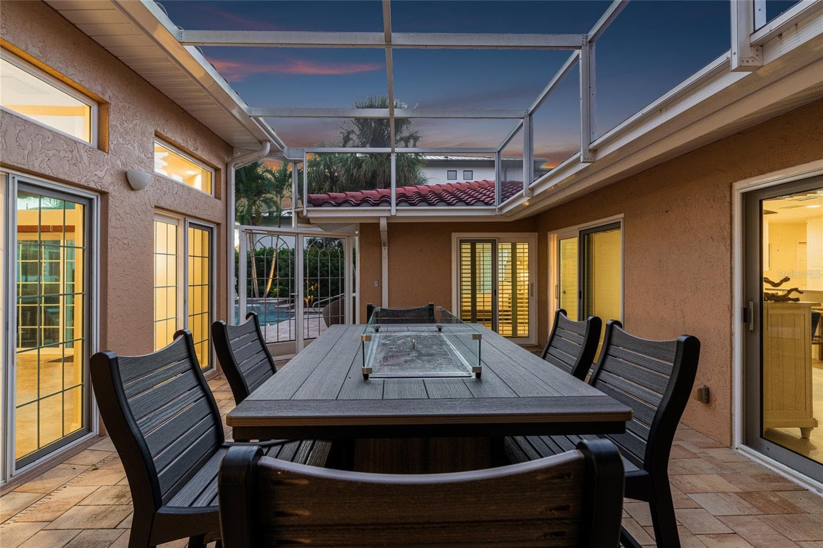 Twilight brings a warm glow to the fully screened central courtyard lanai, complete with a tabletop fire pit. - 5376 SHADOW LAWN DR, SARASOTA
