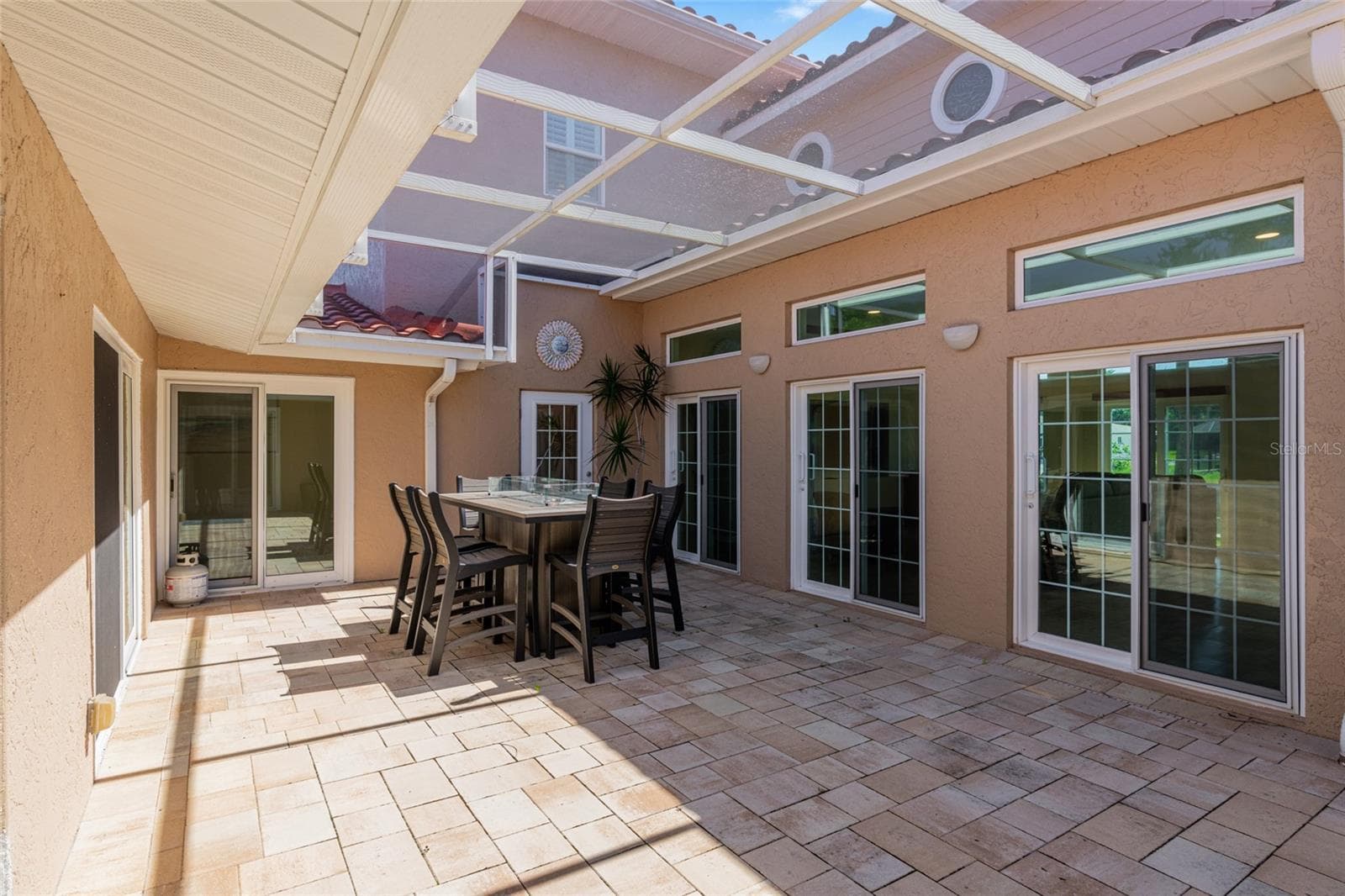 Daytime view of the fully screened courtyard lanai at the center of the home, connecting multiple living spaces with the route toward the pool. - 5376 SHADOW LAWN DR, SARASOTA