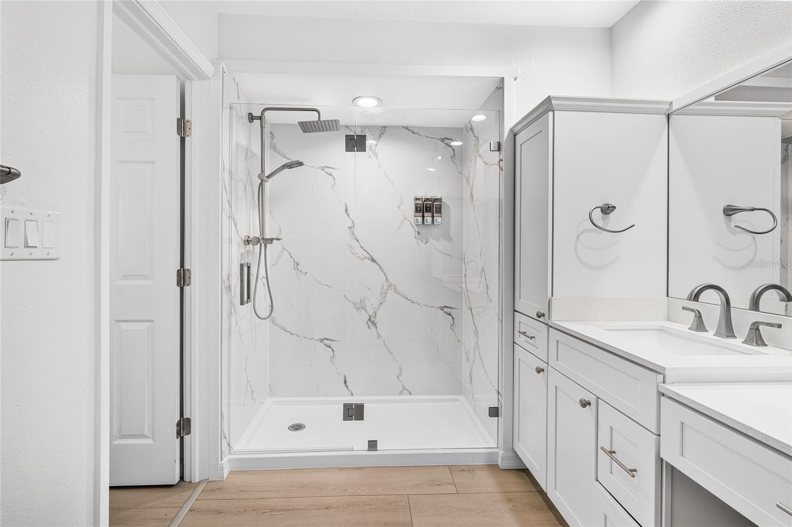 The renovated 2026 first floor primary bath features an oversized shower and upscale finishes. - 5376 SHADOW LAWN DR, SARASOTA