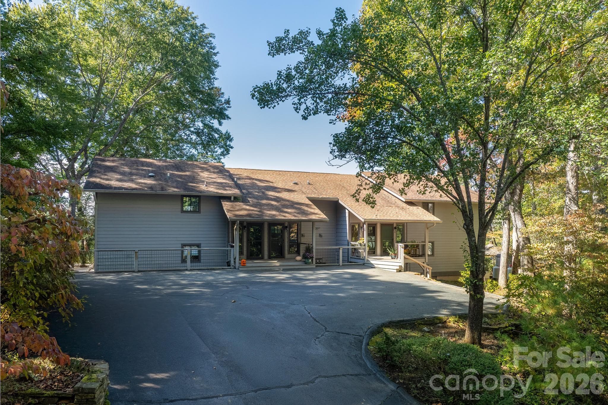Welcoming exterior surrounded by mature hardwoods, featuring a spacious paved parking area and attractive natural setting. - 524 Three Mile Knob Road, Pisgah Forest