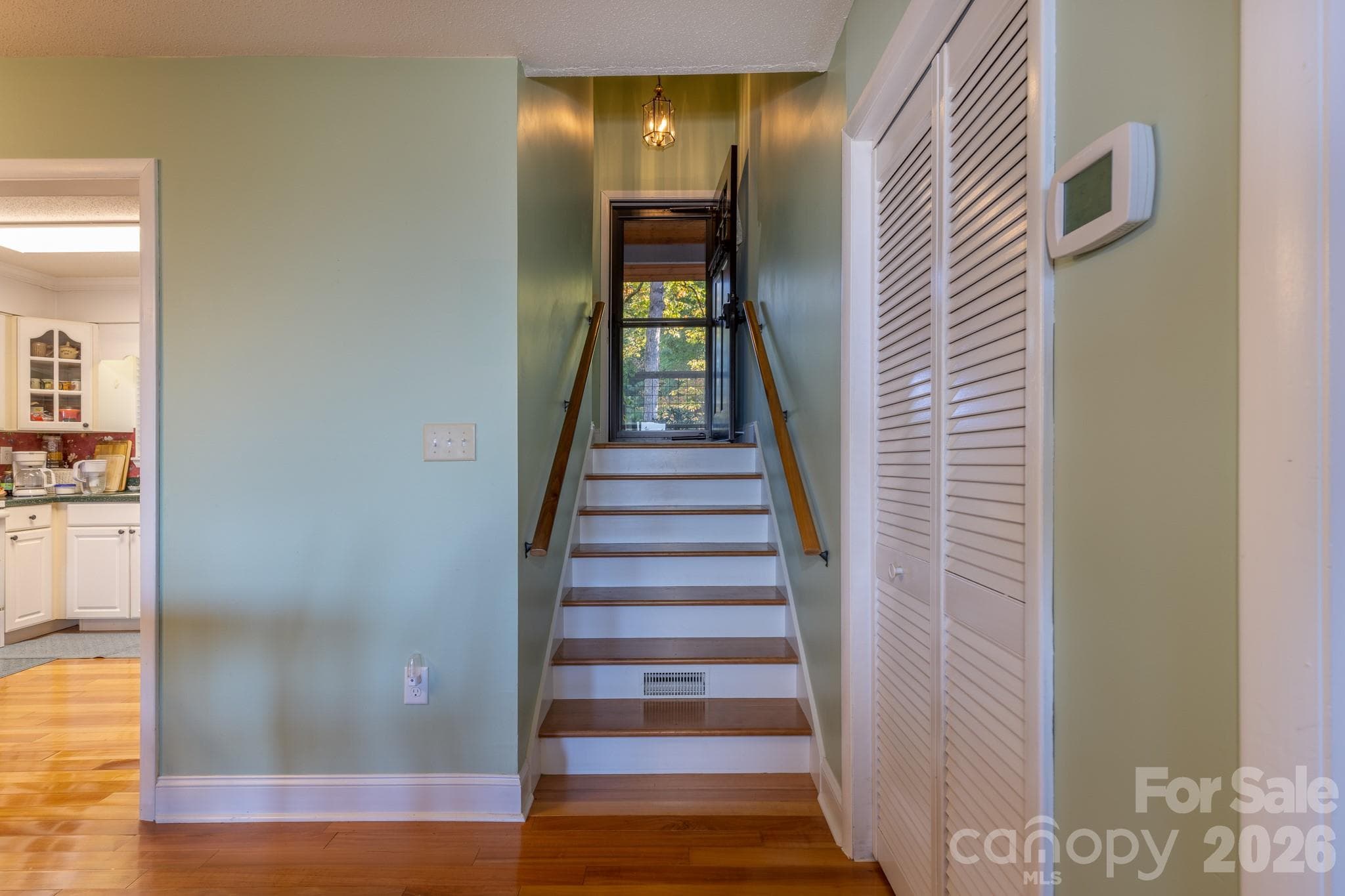Interior stairway featuring hardwood treads, dual handrails, and convenient access to the upper level. - 524 Three Mile Knob Road, Pisgah Forest