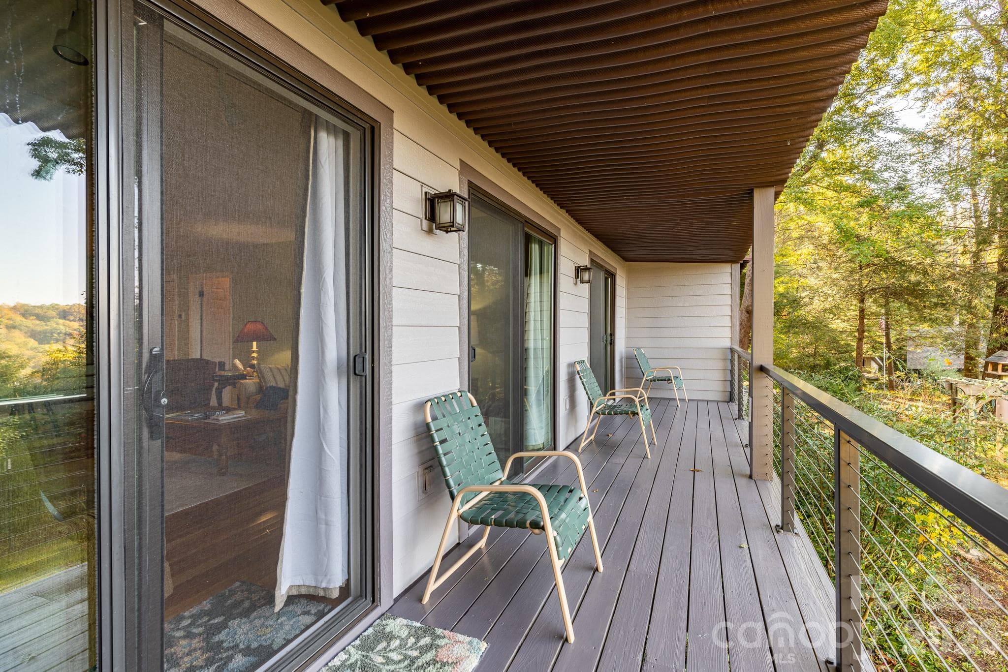 Expansive covered deck with durable decking, cable railing, and peaceful wooded surroundings. A wonderful place to relax and enjoy mountain living. - 524 Three Mile Knob Road, Pisgah Forest