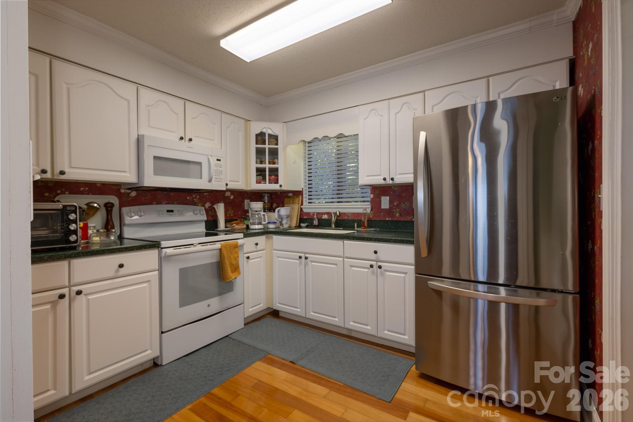 Functional kitchen featuring white cabinetry, generous counter space, Stainless steel French-door refrigerator, electric range, and built-in microwave. - 524 Three Mile Knob Road, Pisgah Forest
