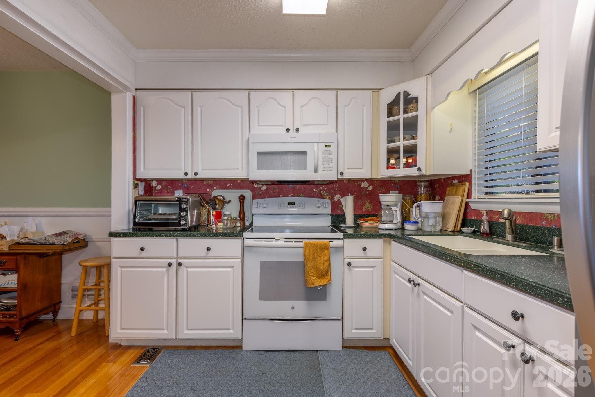 Well-appointed kitchen with abundant white cabinetry, electric range, built-in microwave, and convenient access to the adjoining dining area. - 524 Three Mile Knob Road, Pisgah Forest