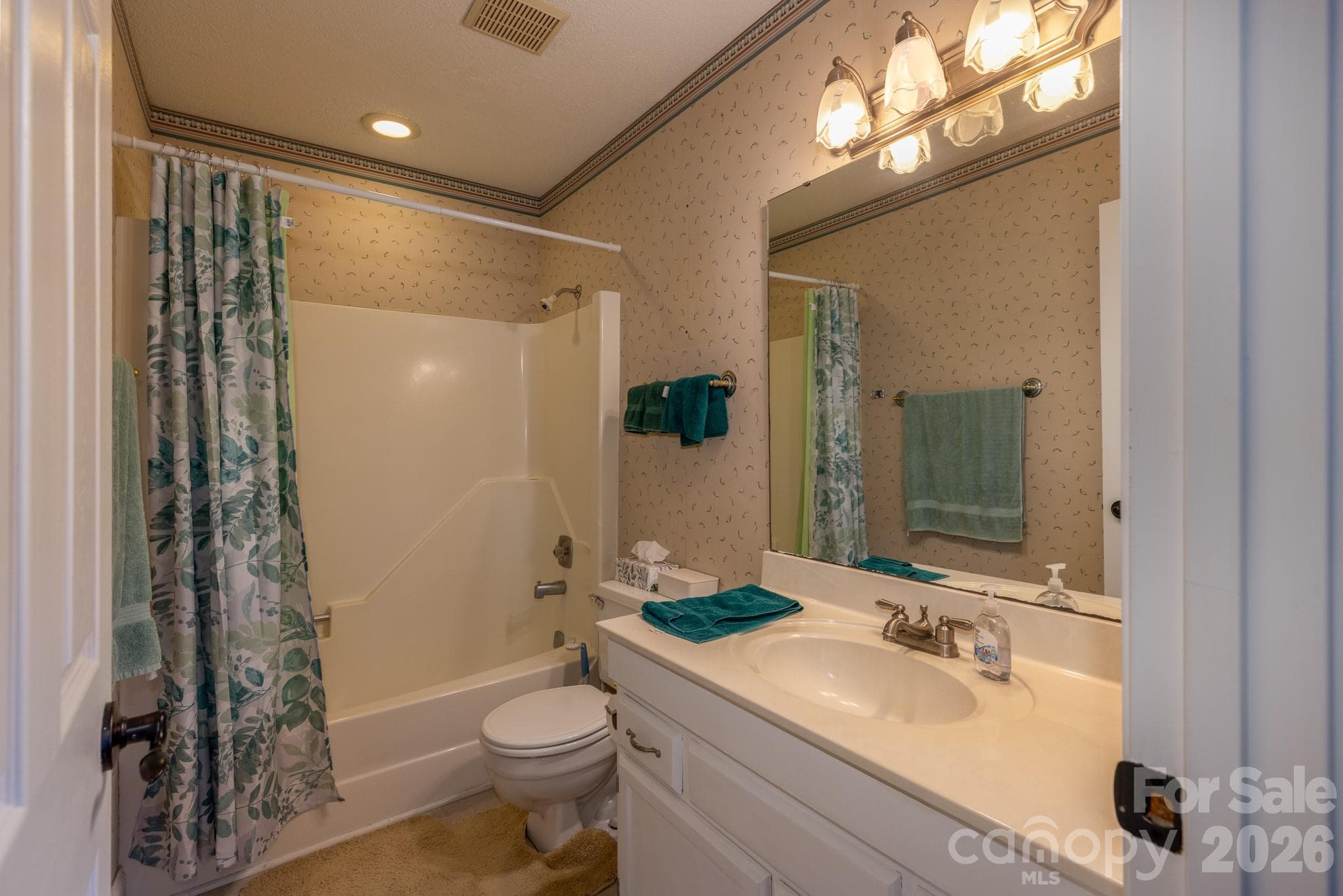 Full bathroom featuring a tub/shower combination, spacious vanity, large mirror, and convenient access from the primary bedroom. - 524 Three Mile Knob Road, Pisgah Forest