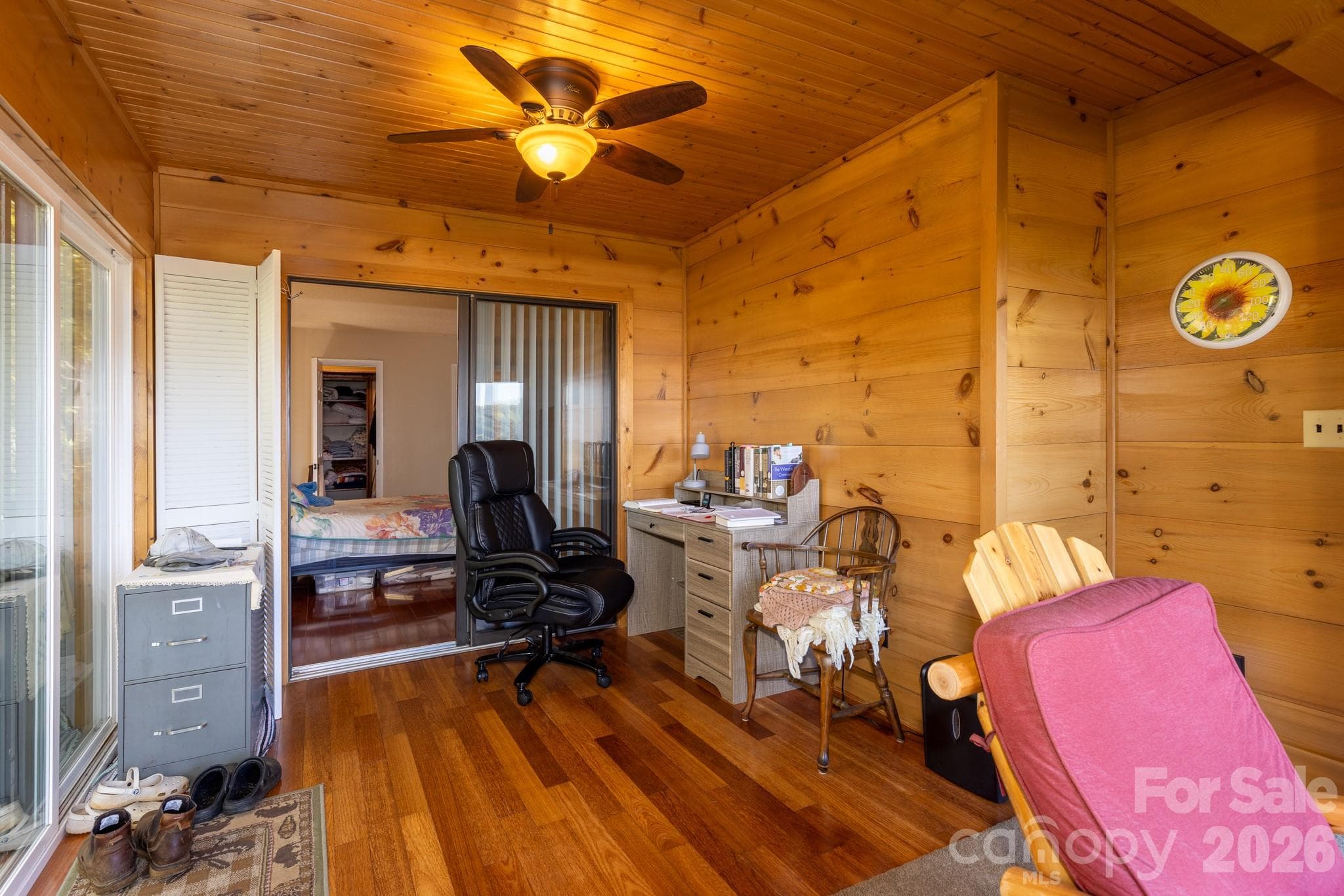 Beautiful wood-paneled sunroom featuring hardwood floors, natural wood walls and ceilings, exposed beams, and flexible space for relaxing or working. - 524 Three Mile Knob Road, Pisgah Forest