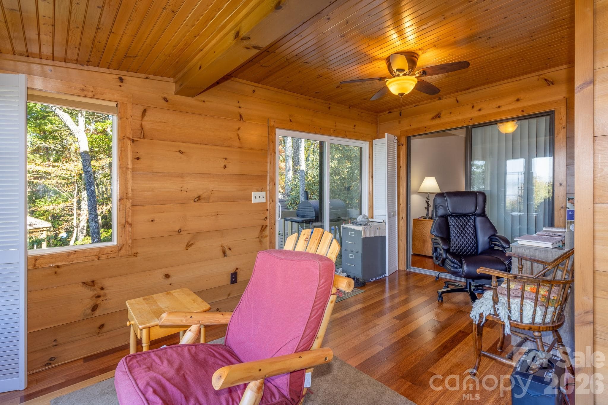 Warm and inviting sunroom with natural wood finishes, ceiling fan, abundant windows, and direct access to the outdoor deck. - 524 Three Mile Knob Road, Pisgah Forest