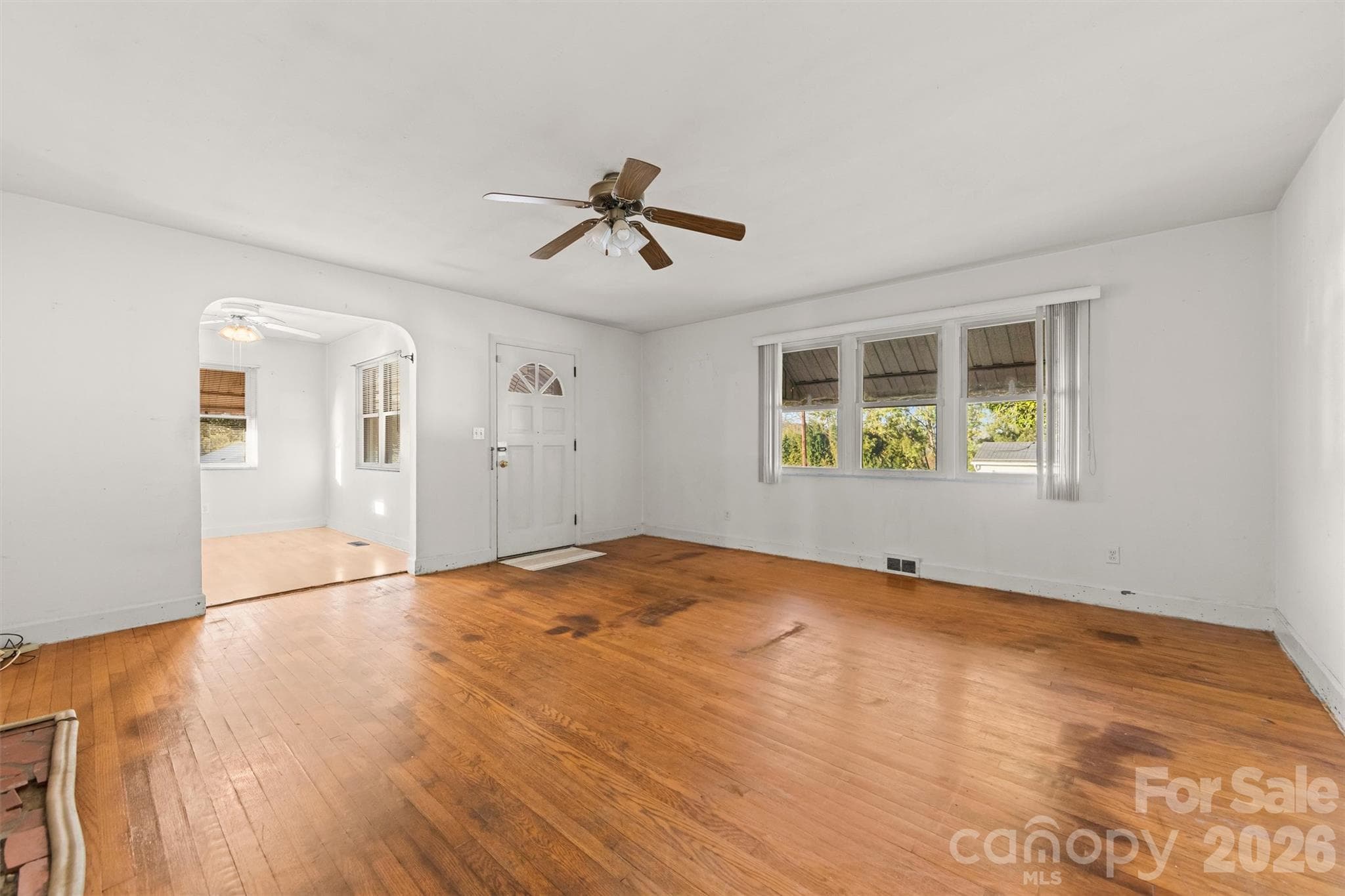 Front windows in the living room with original wood floors and brick fireplace - 108 Morgan Street, Canton