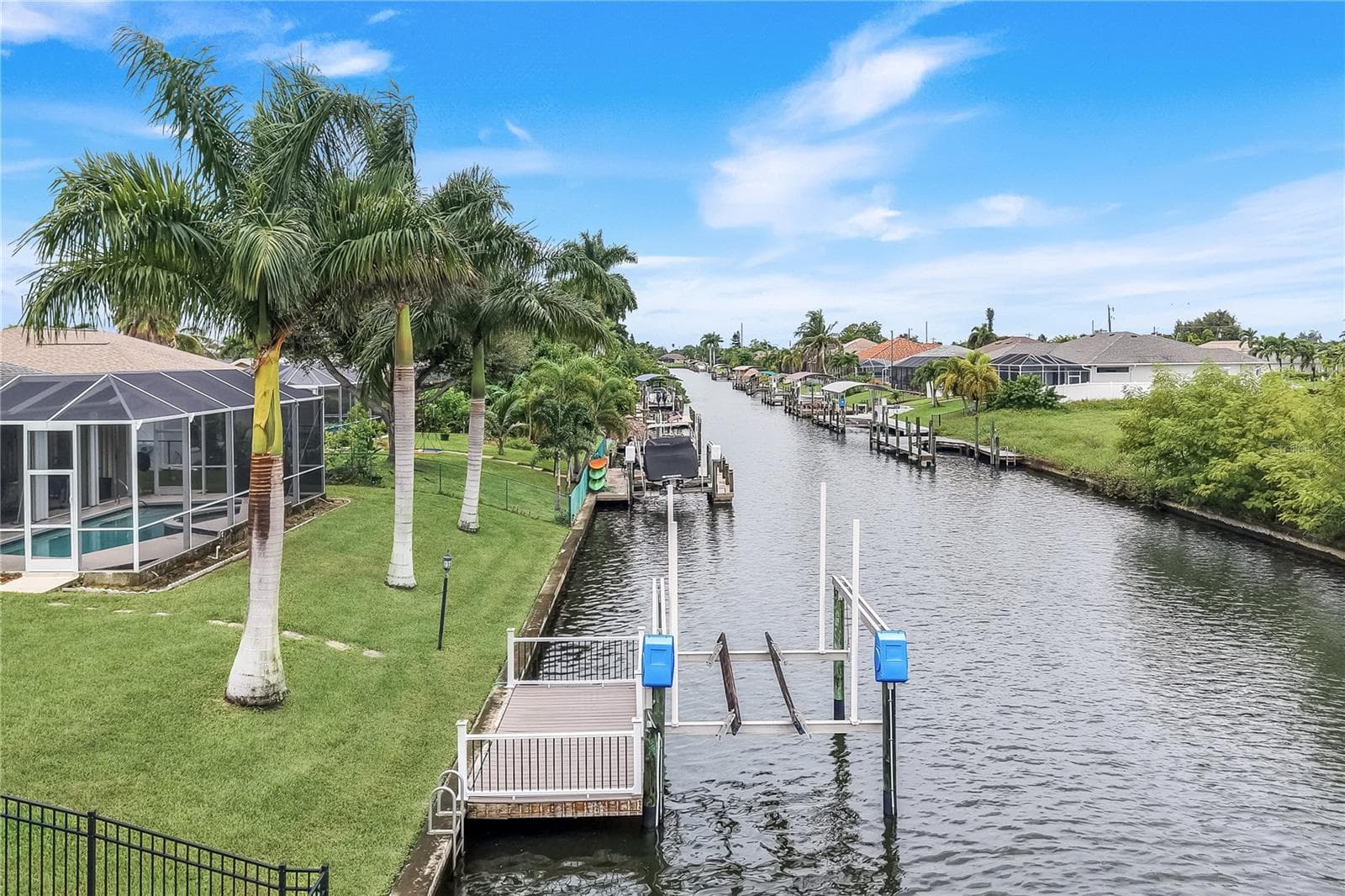 Canal view of the dock, lift and backyard with royal palms. - 305 SE 31ST ST, CAPE CORAL