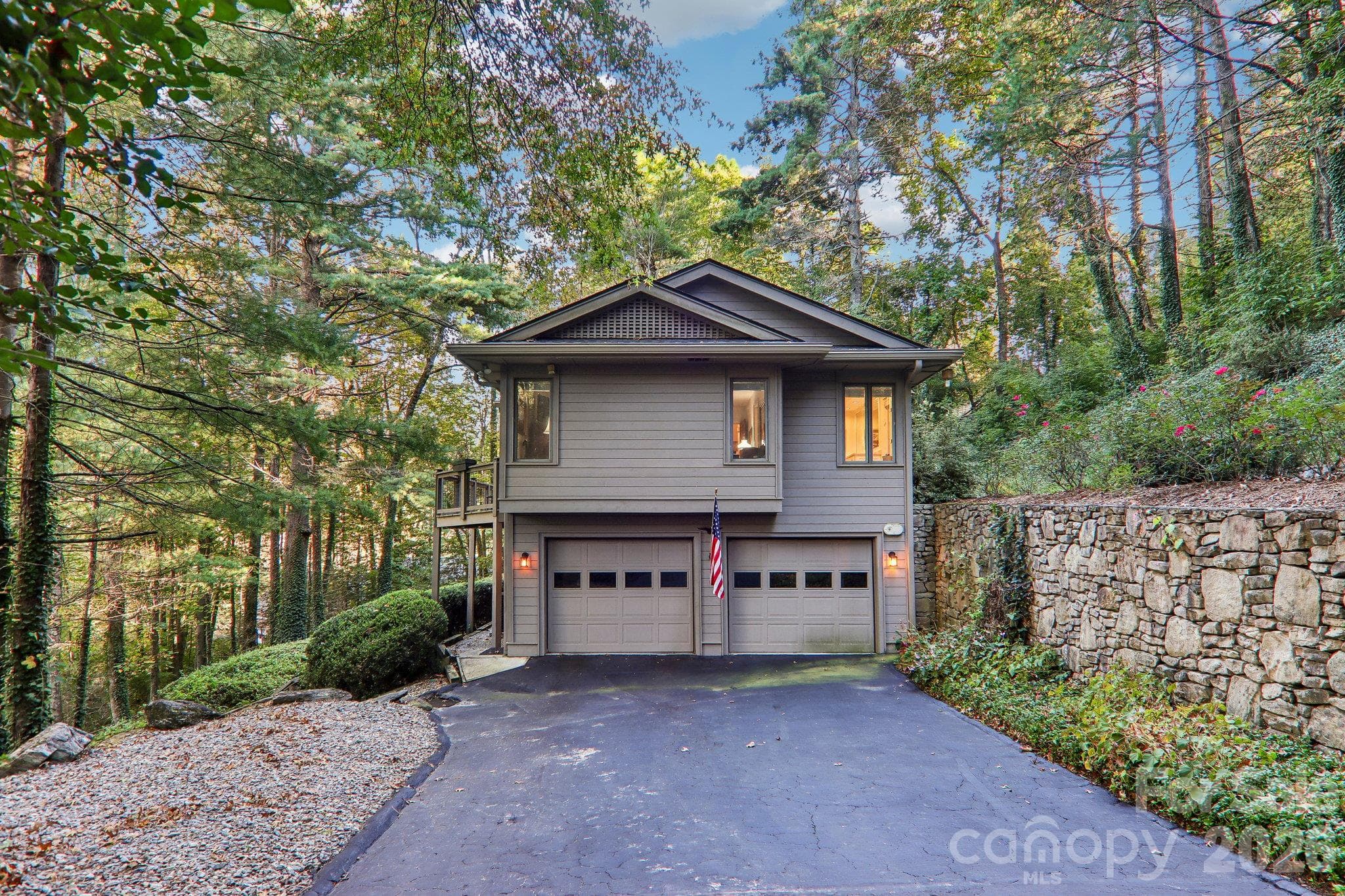 Side of the home with garage entry. Natural rock retaining wall accents the rock work on the home. - 212 Pheasant Run, Hendersonville