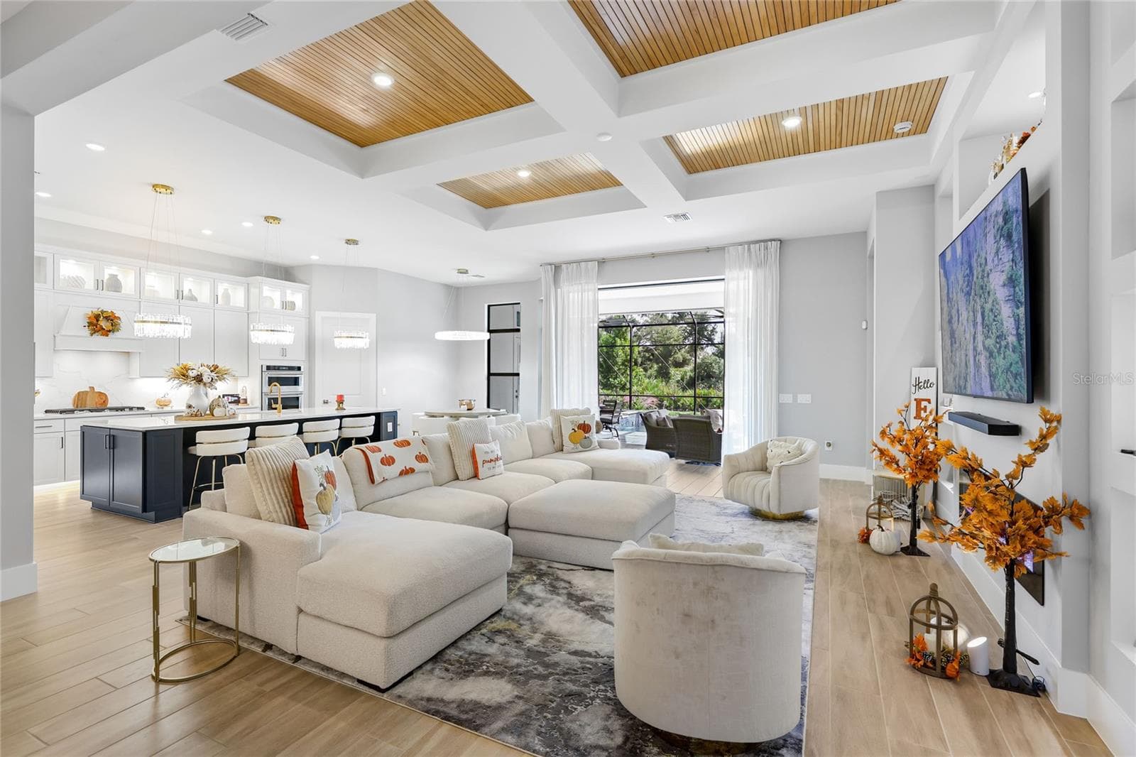 Bright, expansive open-concept living and dining areas featuring soaring ceilings, a coffered ceiling with inset wood trim, elegant architectural details, and expansive windows that fill the home with natural light. - 14726 EAGLE BRANCH DR, NOKOMIS