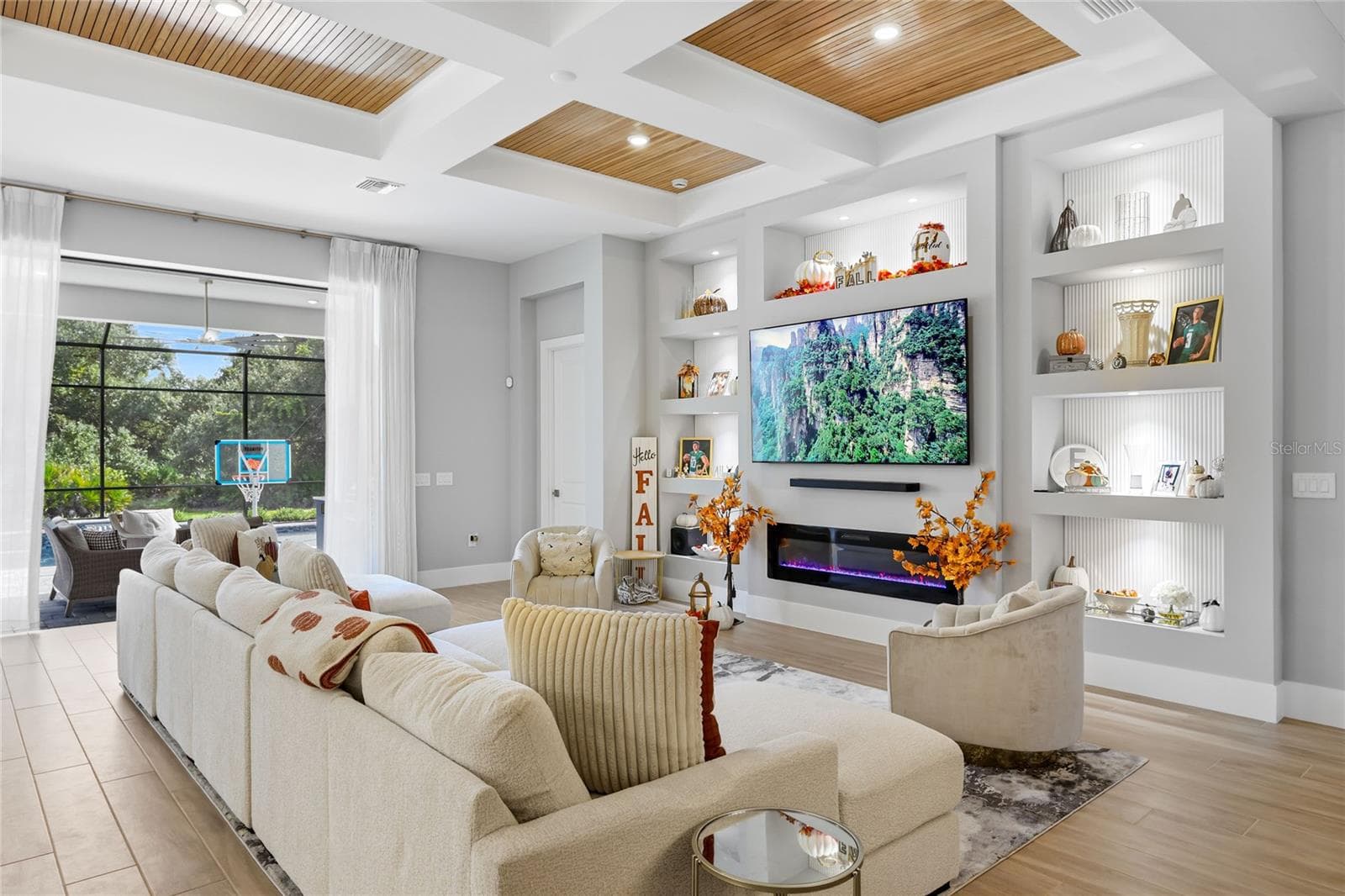 Custom built-in cabinetry with elegant display shelving and a striking fireplace creates a sophisticated focal point in the living room, blending timeless design with warmth and style. - 14726 EAGLE BRANCH DR, NOKOMIS