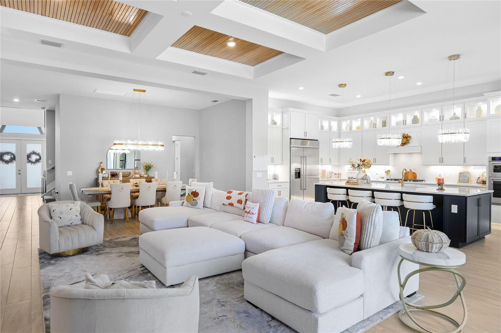 Bright, expansive open-concept living and dining areas featuring soaring ceilings, a coffered ceiling with inset wood trim, elegant architectural details, and expansive windows that fill the home with natural light. - 14726 EAGLE BRANCH DR, NOKOMIS