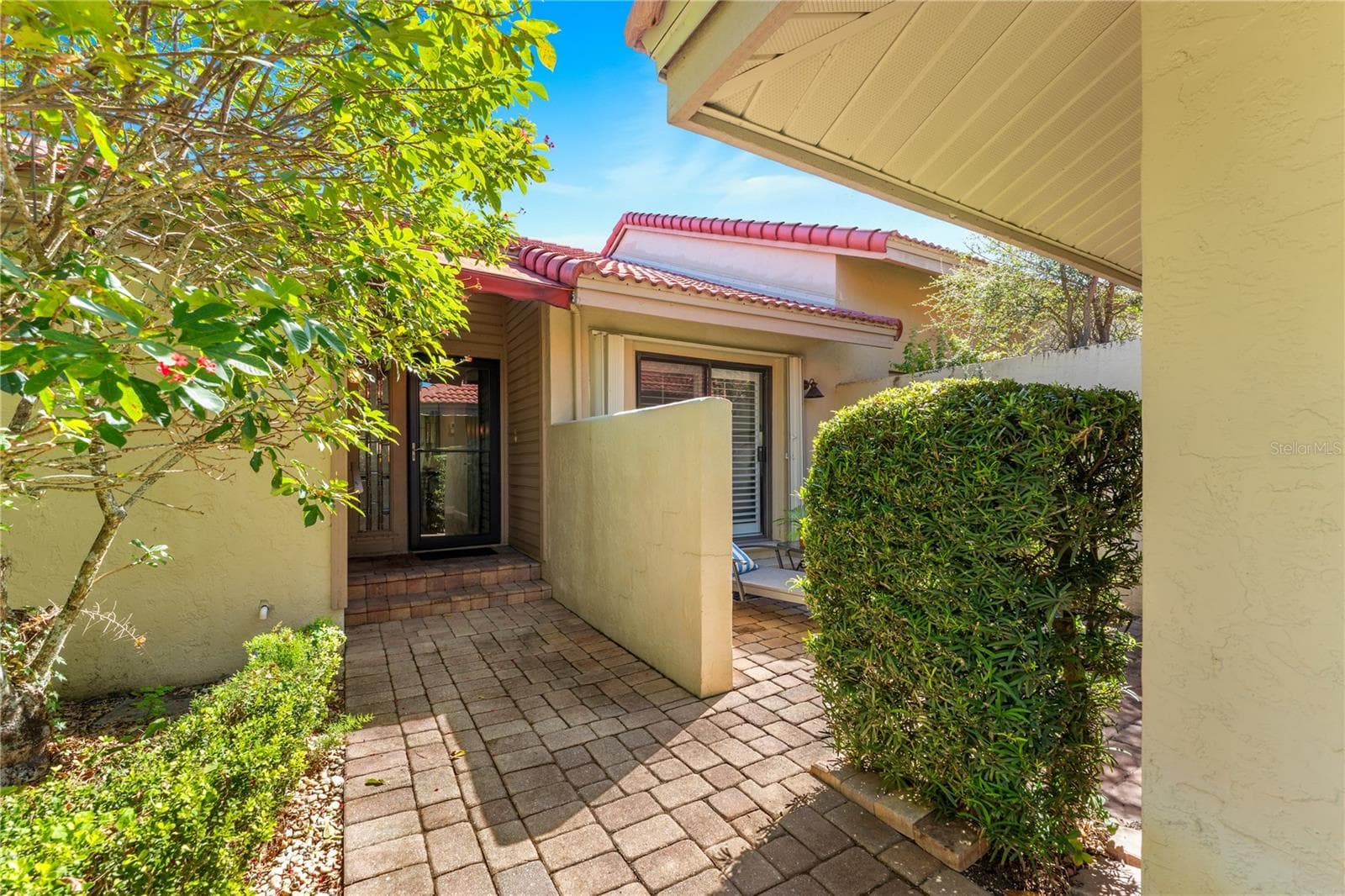 Private entry courtyard featuring paved walkways and mature greenery. - 1720 KESTRAL PARK WAY S #49, SARASOTA