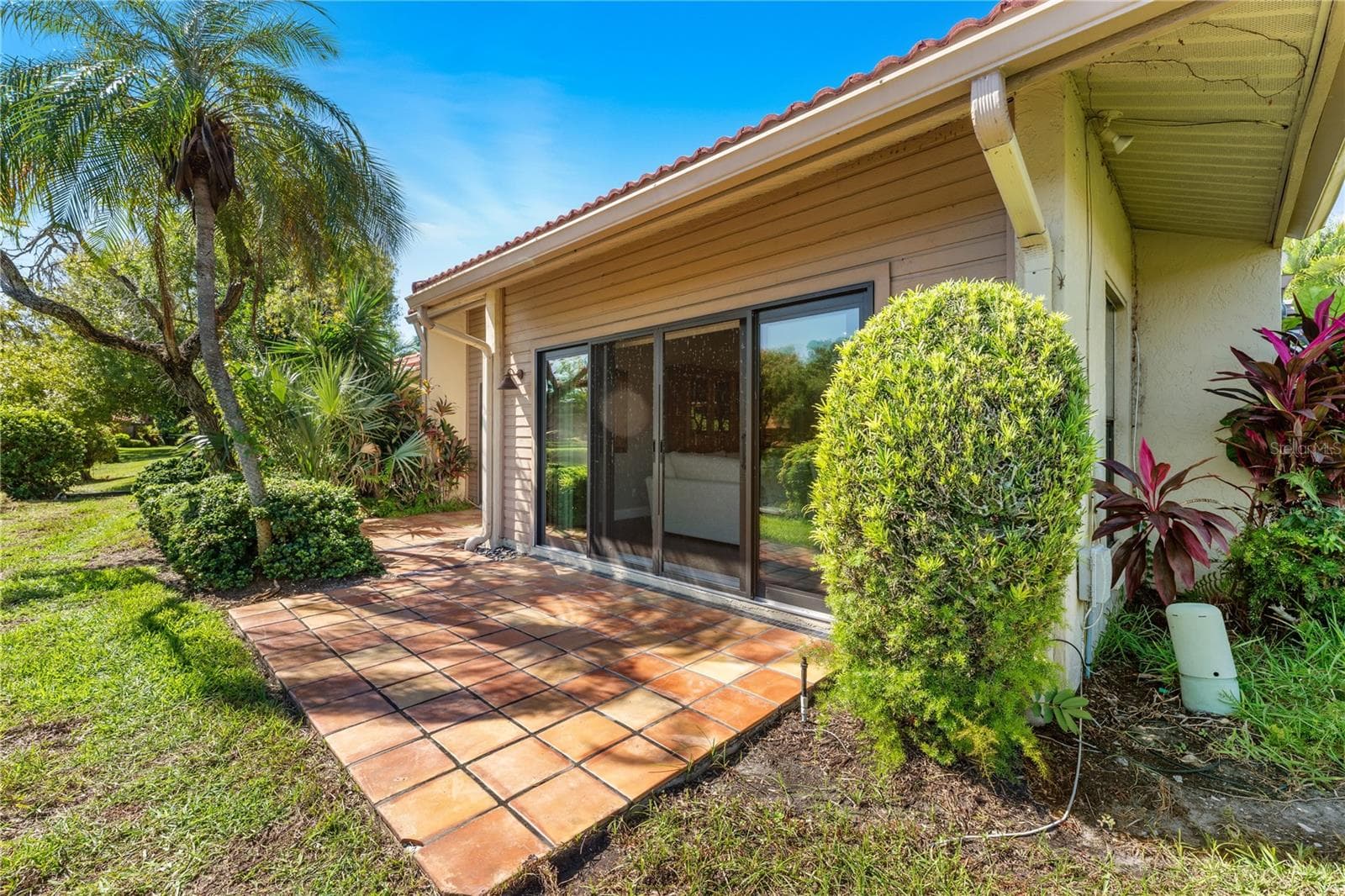 Rear patio terrace framed by mature trees and open water. - 1720 KESTRAL PARK WAY S #49, SARASOTA
