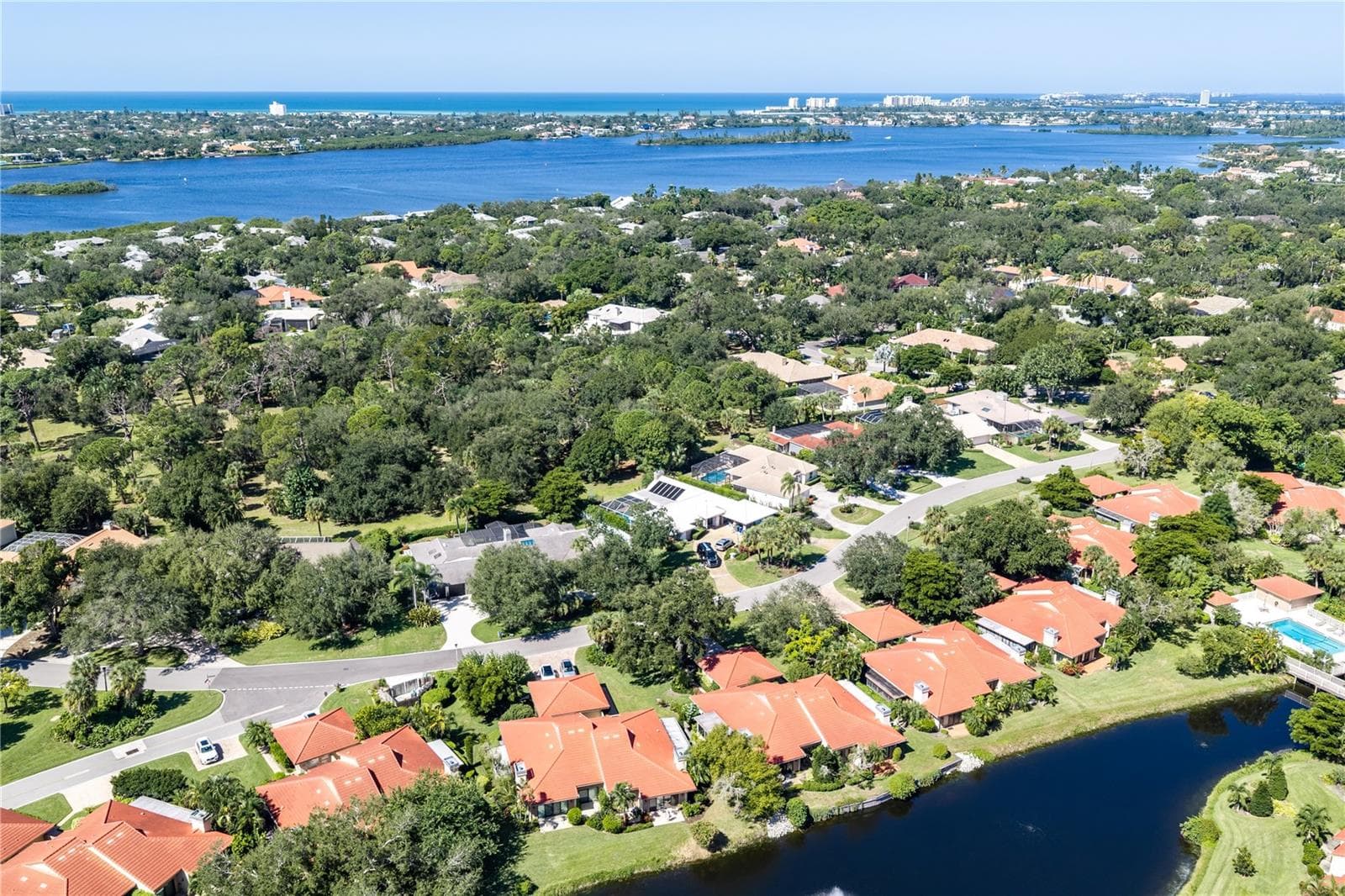 Elevated community view over mature tree canopy lined roads, and Siesta Key. - 1720 KESTRAL PARK WAY S #49, SARASOTA