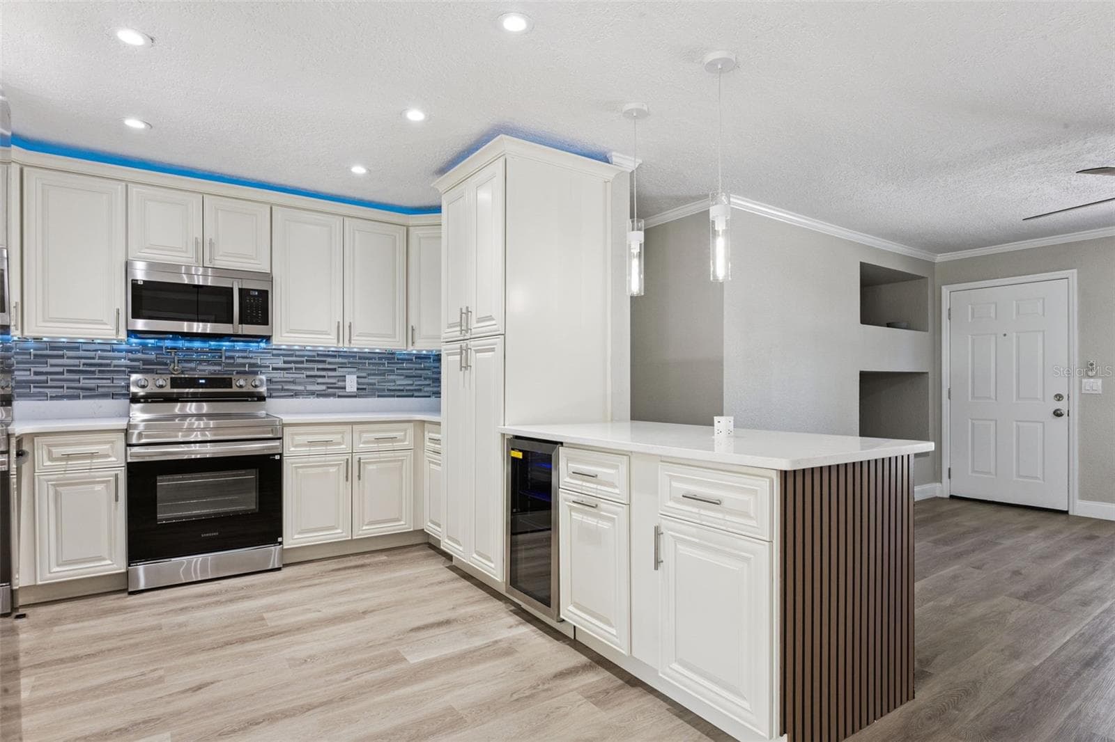Gourmet Kitchen Overview: Upgraded kitchen featuring white raised-panel cabinets, stainless steel appliances, a mosaic tile backsplash, and a breakfast bar peninsula. - 720 GEORGIA AVE, LONGWOOD
